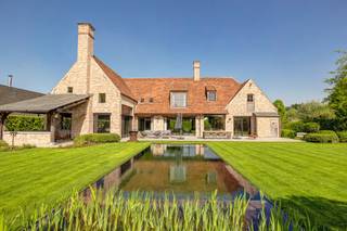 Deze exclusieve villa, gebouwd door het gerenommeerde bouwbedrijf Mattibouw, combineert charme en luxe met hedendaagse technologieën. Er werd gebruik gemaakt van 250 jaar oude derdeling Paepesteen en authentieke tegelpannen. Het indrukwekkend woonvolume en de sublieme afwerking maken dit eigendom uniek.<br /><br />GELIJKVLOERS<br />De inkomhal van 17 m², afgewerkt met Imperial Tiffany’s, straalt grandeur uit en bevat een gastentoilet met handenwasser en ingebouwde vestiairekasten.<br />De woonkamer van 37 m² op brede parketvloeren heeft een ingebouwde haard met warmterecuperatie en een op maat vervaardigd tv-meubel.<br />De eetkamer van 21 m² biedt uitzicht op de aangelegde tuin.<br />De leef-eetkeuken van 49 m² is het hart van de woning. Hier ligt handgetrommelde, gezoete Belgische blauwe hardsteen, gecombineerd met een mezzanine van 15 m² in volle eik.<br />De keuken is uitgerust met een kookeiland en hoogwaardige apparatuur: inductiekookplaat, dubbele oven, twee warmhoudlades, ingebouwde koelkast, vaatwasser van Miele, dampkap, koffiecorner en inbouwcassette. Een schuifraam verbindt de keuken met het terras.<br />De berging van 5 m² op kerkdal biedt extra opslag voor voeding en dranken.<br />De wasplaats van 8 m² met werkblad in blauwe hardsteen is ingericht met inbouwkasten en aansluitingen voor wasmachine en droogkast.<br />De bureauruimte van 27 m² met massieve eiken planken is geschikt om wonen en werken te combineren.<br />Een tweede bureauruimte van 25 m² op parket heeft een kastenwand en wandverlichting.<br /><br />Het terras van 100 m² werd aangelegd in Candela Grey natuursteen en beschikt over een apart toilet met handenwasser.<br />Het overdekt terras van 20 m² op platines is verwarmd.<br />De tuin, aangelegd door Witse’s Tuinen, is een waar kunstwerk.<br />Blikvanger is de natuurlijke zwemvijver met hoogwaterlijn en biologisch filtersysteem.<br />De poolhouse/garage van 44 m² werd in dezelfde afwerkingsgraad gebouwd en is bereikbaar via een aparte oprit in kasseien met automatische poort.<br /><br />1STE VERDIEPING<br />De overloop van 30 m² op parket leidt naar het mastergedeelte, een nachttoilet en meerdere kamers.<br />De hoofdslaapkamer van 22 m² kijkt uit op de tuin en grenst aan een ensuite dressing van 19 m² op parket.<br />De ensuite badkamer van 19 m² op tegel beschikt over ligbad, inloopdouche, dubbel lavabomeubel, spiegel en toilet, afgewerkt met microcement.<br />Een polyvalente ruimte van 53 m² kan gebruikt worden als fitness of worden opgedeeld in kamers.<br />Er zijn twee slaapkamers van elk 14 m² op parket en een tweede badkamer van 6 m² met inloopdouche en lavabomeubel.<br /><br />2DE VERDIEPING<br />Een ruime opbergzolder is bereikbaar via een vlizotrap.<br /><br />ONDERGRONDSE VERDIEPING<br />De kelder van 326 m² is ideaal voor autoliefhebbers of wijnverzamelaars.<br />Er is een wijnkelder van 25 m², opslagruimte met ingemaakte kasten, werkplaats van 34 m² met krachtstroom en een ondergrondse garage van 244 m² met plaats voor zeven wagens.<br /><br />TECHNIEK EN VEILIGHEID<br />Verwarming en koeling via geothermische warmtepomp.<br />Domoticasysteem van Nico Home Control voor aansturing van verlichting, verwarming en gordijnen.<br />Beveiliging met raam- en deurcontacten en warmtecamera’s.<br />Ventilatiesysteem type D.<br />Ramen uit Afrikaans hardhout en aluminium met vierseizoensglas.<br />380V-stroomvoorziening, UTP-aansluitingen in elke ruimte, Daikin-airconditioning.<br />Regenwaterput van 20.000 liter, geboorde waterput van 90 meter diep en automatisch beregeningssysteem.<br /><br />POSITIEVE ASPECTEN<br />EPC-label A<br />100% privacy<br />High-end afwerking<br />Sterk beveiligd<br />Zuid-west georiënteerde tuin<br />Rustige residentiële omgeving<br />Ideale combinatie wonen en werken