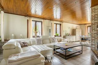 Voor meer info en foto’s, surf naar www.swevers.be – Op een ruim perceel van 980 m² in Heusden-Zolder ligt deze vrijstaande woning met een bewoonbare oppervlakte van circa 190 m². De woning werd gebouwd in 1992 en biedt dankzij haar solide structuur en ruime indeling een uitstekende basis voor wie op zoek is naar een gezinswoning die volledig naar eigen smaak kan worden opgefrist. Via de inkomhal met gastentoilet bereikt u de lichtrijke woonkamer van 42,25 m², waar voldoende ruimte is voor een gezellige zithoek en eetplaats. De aansluitende keuken van 16,20 m² biedt tal van mogelijkheden voor een eigentijdse inrichting. Daarnaast beschikt het gelijkvloers over een aparte bureauruimte en een ruime inpandige garage van 39,38 m² met plaats voor voertuigen, fietsen en extra opslag. Op de verdieping bevinden zich drie volwaardige slaapkamers. De master bedroom van ongeveer 17 m² beschikt over een aparte dressing. De twee overige slaapkamers zijn elk circa 12,26 m² groot. Verder zijn er een badkamer en een afzonderlijk toilet aanwezig. Een absolute meerwaarde is de uitzonderlijk ruime kelder van 109,45 m², ideaal als opslagruimte, hobbyruimte, werkplaats of fitness. Buiten geniet u van een zonnige, zuidgerichte tuin waar rust, privacy en ruimte centraal staan. De open bebouwing versterkt het gevoel van vrijheid en biedt tal van mogelijkheden voor verdere tuininrichting. De woning is gunstig gelegen met scholen op 800 meter, openbaar vervoer op 750 meter, winkels op 1,9 kilometer, restaurants op 1,5 kilometer en een vlotte verbinding naar de snelweg op 5,8 kilometer. Voor meer informatie, bel 011 255 155. Bron bewoonbare oppervlakte: EPC – verslag.