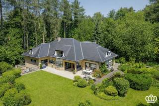 <p><span>Residentieel gelegen villa op een privacyrijk perceel van 2.672 m², tegenover een natuurgebied en nabij het centrum van Heide-Kalmthout, met o.a. een ruime en lichtrijke leefruimte, leefkeuken, vijf royale slaapkamers, drie ingerichte badkamers en een wellnessruimte met binnenzwembad en sauna.  </span></p><p><span>INDELING</span></p><p><span>Gelijkvloers</span></p><p><span>U betreedt de woning via een ruime inkomhal op natuurstenen vloer, voorzien van een gastentoilet met handenwasser en een vestiaire. Deze hal geeft toegang tot de royale en lichtrijke leefruimte op parketvloer, onderverdeeld in een tv-hoek, een zithoek met erker en gashaard en een eetruimte.</span></p><p><span>Aansluitend bevindt zich de volledig uitgeruste leefkeuken met alle hedendaagse toestellen, waaronder een combi-oven, microgolf, inductievuur met ingebouwde dampkap, spoelbak met Quooker-kraan, een grote koelkast, een vriezer en een vaatwasser. De ontbijthoek biedt directe toegang tot het overdekte terras met uitzicht op de prachtig aangelegde tuin.</span></p><p><span>Daarnaast beschikt het gelijkvloers over een masterbedroom op laminaatvloer met aansluitend een dressing en een ingerichte badkamer. Deze is uitgerust met een inloopdouche voorzien van een infrarood Sunshower, een ligbad, dubbele wastafel, toilet en handdoekenradiator.</span></p><p><span>Ten slotte is er nog een dubbele inpandige garage met automatische poort, waar zich eveneens de aansluitingen voor wasmachine en droogkast bevinden.</span></p><p><span> </span></p><p><span>Eerste</span><span> </span><span>verdieping</span></p><p><span>Via de royale trap met vide bereikt u de nachthal, waar zich een apart toilet en een bergkast bevinden. Bovendien heeft u toegang tot een knus balkon. Op deze verdieping bevinden zich vier zeer ruime slaapkamers en een tweede badkamer, ingericht met een douche, ligbad, wastafel, toilet en handdoekenradiator.</span></p><p><span> </span></p><p><span>Zolder</span></p><p><span>Via een vlizotrap heeft u toegang tot de bergzolder.</span></p><p><span> </span></p><p><span>Kelder</span></p><p><span>Middels de centrale trappartij bereikt u de kelder, opgedeeld in drie compartimenten: een bergruimte, een technische ruimte en een ontspanningsruimte. Deze laatste is uitgerust met een zwembad (4 m x 9 m) met jetstream, een traditionele sauna en een badkamer voorzien van een douche, wastafel en toilet. Via een schuifdeur heeft u toegang tot een aangenaam omsloten terras.</span></p><p><span> </span></p><p><span>Tuin</span></p><p><span>De woning is gelegen op een volledig omheind perceel van ca. 2.650 m². De prachtig aangelegde tuin die volledige privacy biedt en veel zoninval geniet, is voorzien van een irrigatiesysteem en meerdere vijverpartijen, die bijdragen aan een rustgevende en groene leefomgeving.</span></p><p><span>Bijzonderheden</span><span><br />-Charmante villa in klassieke/tijdloze stijl <br />-Recent gemoderniseerd o.a. keuken, badkamers, vloeren, …. <br />-Verrassend ruim<br />-Volledige privacy <br />-Fraai aangelegde en goed onderhouden tuin met veel zoninval<br />-Zuid-west georiënteerd<br />-Goed beveiligd<br />-Binnenzwembad en sauna in de kelder met buitenterras<br />-Rustig in het groen gelegen, tegenover natuurgebied en nabij dorpscentrum (scholen, winkels en  openbaar vervoer). <br />-Elektrische keuring is conform.<br />-Geen asbest</span></p><p><span> </span></p>
