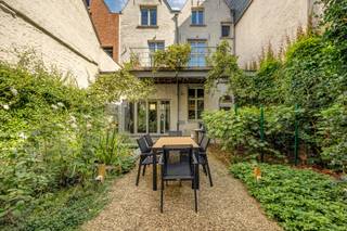 Karaktervolle trapgevelwoning met tuin en twee terrassen. Verscholen achter een authentieke trapgevel, in één van de mooiste straatjes van de binnenstad, ligt deze sfeervolle stadswoning waar eeuwenoud karakter en hedendaags wooncomfort elkaar moeiteloos vinden. Balken, blauwe hardsteen en een verzorgde tuin met vijver zetten meteen de toon van een woning met een verhaal.<br /><br /><u>Binnenkomen met karakter</u><br />Achter de statige gevel opent een royale inkomhal van ±21 m² op blauwe hardsteen, met apart gastentoilet. De living van ±36 m², eveneens op blauwe steen en voorzien van ingemaakte kasten, geeft rechtstreeks uitzicht op de aangelegde tuin (±88 m²) met vijver — een groene oase midden in de stad, ideaal om tot rust te komen of gasten te ontvangen.<br /><u>Wonen onder authentieke balken</u><br />Op de eerste verdieping tovert een imposant balkenplafond het salon (±32 m²) om tot een warme, karaktervolle ruimte. Grote raampartijen met rijkelijk daglicht en een aangrenzend terras op bankirai (±11 m²) maken dit de perfecte plek voor een ontspannen avond. De aansluitende eetplaats (±18 m²) op houten vloer leent zich uitstekend voor gezellige diners, terwijl de volledig uitgeruste keuken (±16 m²) met kookeiland, dubbele spoeltafel, gasfornuis, oven, koelkast, diepvriezer, vaatwasser en dampkap niets te wensen overlaat.<br /><u>Rustige nachtvleugel</u><br />Via de nachthal op de tweede verdieping bereikt u twee ruime slaapkamers (±18,5 m² en ±18 m²), beide met houten vloer, en een verzorgde badkamer (±5,5 m²) met douche, wastafelmeubel en hangtoilet.<br />Extra troeven<br />Een deels gewelfde kelder, onderverdeeld in vier ruimtes (±18,5 m², ±15 m², ±15 m² en ±18 m²), biedt eindeloos veel bergruimte of ontwikkelingspotentieel. De woning is voorzien van CV op gas.<br /><u>Ligging</u><br />Centraal gelegen in het historische hart van de stad, tussen karakteristieke gevels en op wandelafstand van winkels, horeca en de belangrijkste bezienswaardigheden — wonen met alle stadscomfort binnen handbereik, en toch helemaal tot rust komen in uw eigen tuin.<br /><br />Interesse of een bezoek inplannen? Neem gerust contact op met Immobiliën Carl Martens.<br /><br />