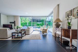<h3>Exclusieve architectenvilla op toplocatie in villawijk De Lint</h3>
<p>Op een prachtig zuidwestgericht perceel, op wandelafstand van het unieke natuurgebied De Liereman, bevindt zich deze hedendaagse en onder architectuur gebouwde villa. Deze uitzonderlijke woning combineert tijdloze architectuur, royale leefruimtes en een hoogwaardig afwerkingsniveau met een uitstekende bereikbaarheid. Zowel Eindhoven als Antwerpen bevinden zich op slechts ca. 25 minuten rijden, waardoor u geniet van het beste van twee werelden: rust, natuur en een vlotte verbinding.</p>
<p>Bij aankomst wordt u verwelkomd in een ruime inkomhal met vestiaire en gastentoilet. Via stijlvolle dubbele deuren betreedt u de indrukwekkende woonkamer, waar de grote raampartijen een panoramisch zicht bieden op de prachtig aangelegde tuin. Het overvloedige natuurlijke licht en de fraaie tuinzichten creëren een unieke woonbeleving. Aansluitend bevindt zich een open ruimte die perfect dienst kan doen als bureau of leeshoek, open van karakter maar toch afzonderlijk van de leefruimte.</p>
<p>De sfeervolle doorkijkhaard vormt een elegante verbinding tussen de woonkamer en de royale leefkeuken. Deze keuken verkeert in perfecte staat van onderhoud, is uitgerust met kwalitatieve toestellen, beschikt over een groot werkblad en biedt plaats aan een ruime eettafel. Dankzij de grote schuiframen loopt binnen naadloos over in buiten. Achter de keuken bevinden zich een praktische bijkeuken en een aparte wasruimte. De inpandige dubbele garage met automatische poort en personenlift vervolledigt het comfort op het gelijkvloers.</p>
<p>Op de verdieping geeft de royale nachthal toegang tot de indrukwekkende master suite met inloopdressing en een luxueuze badkamer. Daarnaast zijn er nog twee volwaardige slaapkamers met een gedeelde badkamer. De ruime studiekamer kan eenvoudig worden ingericht als vierde slaapkamer en beschikt bovendien over een eigen terras.</p>
<p>Ook buiten weet deze villa te imponeren. De volgroeide, volledig omheinde tuin biedt optimale privacy en vormt een waar groen paradijs. Meerdere zonneterrassen en een overdekt terras nodigen uit om in alle seizoenen van het buitenleven te genieten. Het extra losstaande garagegebouw biedt bijkomende mogelijkheden voor wagenliefhebbers, hobbyruimte of extra opslag.</p>
<p>Naast het uitzonderlijke wooncomfort onderscheidt deze villa zich door haar onderhoudsvriendelijke karakter. Dankzij de duurzame aluminium raamprofielen en de kwalitatieve gevels in gevelsteen zijn er geen schilderwerken aan het buitenschrijnwerk of de buitenmuren nodig, wat resulteert in een stijlvolle uitstraling met een minimum aan onderhoud.<br /><br /><strong>Een uitzonderlijke villa voor wie ruimte, comfort, privacy, kwaliteit en een onderhoudsarme woonomgeving weet te waarderen.</strong></p>
<h3>Troeven van deze woning</h3>
<ul>
<li>Wandelafstand van natuurgebied De Liereman</li>
<li>Zuidwestgericht perceel met optimale bezonning</li>
<li>Personenlift naar de verdieping</li>
<li>Vloerverwarming op gelijkvloers én verdieping</li>
<li>Inpandige dubbele garage met automatische poort</li>
<li>Extra losstaand garagegebouw met bergzolder</li>
<li>Alarmsysteem</li>
<li>Zonnescreens</li>
<li>Fraai aangelegde, volledig omheinde tuin</li>
<li>Grote terrassen en overdekt, verwarmd terras</li>
</ul>