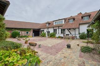 <strong>Prachtige vierkantshoeve met binnenkoer op een uitgestrekt perceel van 1ha43a15ca.</strong> <br />Dit bijzonder vastgoed is gelegen op de Knipscheerstraat 50 in het rustige Alken; omgeven door weilanden én met een vlotte verbinding naar belangrijke invalswegen. Het pand is oorspronkelijk opgetrokken rond 1850 en door de huidige eigenaars grondig gerenoveerd in de jaren '90 met behoud van originele elementen. <span>Kwaliteit, privacy en authenticiteit staan hier centraal. Het pand biedt zeer veel mogelijkheden gezien de beschikbare bewoonbare oppervlakte van 356m² (woongedeeltes), de aanwezigheid van de stallen en van het bijkomende woonhuis (zonder busnummer).</span><br /><br />De imposante toegangspoort leidt naar de binnenkoer die het woongedeelte verbindt met de stallingen en autobergplaats aan de rechterzijde en een tweede woongelegenheid die momenteel dienst doet als bureel.<br /><br />Het <span>eerste woongedeelte</span> is ingedeeld in een inkomhal met gastentoilet en toegang tot de ingerichte keuken. De woonkamer bestaat uit een eethoek met zitplaats en open haard, een bar en een extra zitgedeelte. Deze ruimtes zijn verdeeld over verschillende niveaus. Prachtig zicht op het groen en de vijver. Verder is er nog een wasplaats/berging en een bureel. Op de eerste verdieping is er een ruime overloop die dienst doet als extra TV-kamer, de masterbedroom met dressing en ruime badkamer, een tweede slaapkamer met sanitaire voorzieningen en een 3de slaapkamer die zowel toegankelijk is via de masterbedroom als via het tweede woongedeelte. De woning is deels onderkelderd en hierin zijn de CV-ketels ondergebracht.<br /><br />Het <span>tweede woongedeelte</span> is gelegen aan de achterzijde van het pand en heeft een aparte ingang. Dit woongedeelte is ingedeeld in een inkomhal met een gastentoilet, een woonkamer (momenteel ingericht als bureel en een keukenhoek). Op de eerste verdieping is er een badkamer en twee slaapkamers. Er is een derde kamer die toegang biedt tot de hoofdwoning. <br /><br />De charmante binnenkoer is de plaats bij uitstek om in alle privacy tot rust te komen en te genieten op één van de (overdekte) terrassen.<br />In de ruime <span>garage</span> kan men minstens twee wagens parkeren. De <span>stallingen</span> hebben in het verleden steeds gediend als atelier en kunnen na renovatie en het verkrijgen van een vergunning verder naar wens ingericht worden.<span><br /><br /></span>De tuin is volledig omheind en aangelegd in Engelse stijl en biedt plaats aan meerdere terrassen. De weide en stal zijn ideaal om dieren te houden. Tot slot is er nog een boomgaard met meerdere fruitbomen. <br /><br />De elektriciteit is conform aan de strenge normen van het AREI. <br />Zeer gunstig EPC label C (dubbele verwarmingsinstallatie op aardgas).<br /><br />Kortom: ben jij op zoek naar een authentieke hoeve op een weids perceel in een uiterst groene omgeving? <span>Neem dan vandaag nog contact op voor een bezichtiging en ontdek dit uniek pand met eigen ogen. <br /><br />Wij <strong>ontzorgen</strong> je ook voor de <strong>verkoop van je huidige woning</strong>! Voor meer uitleg helpen we je graag verder.</span>