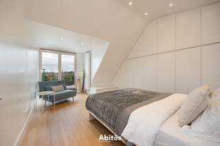 Deze parel aan het Sluizeken, in het centrum van Gent, is een uitgelezen keuze voor wie wil genieten van een adembenemend uitzicht over de historische binnenstad. Het penthouse bevindt zich op de vierde verdieping, wordt gemeubeld verhuurd en beschikt over alle voorzieningen voor een comfortabel verblijf. Ook de omgeving maakt deze woonplek bijzonder: gezellige restaurants, sfeervolle cafés, boetieks en winkels liggen op wandelafstand. De historische straatjes nodigen uit om de stad te voet te ontdekken en volop te genieten van het culturele en culinaire aanbod van Gent.<br /><br />Bij binnenkomst wordt u verwelkomd in de inkomhal, waar een trap naar de bovenverdieping leidt. De hal biedt toegang tot een afzonderlijk toilet, een berging en de royale leefruimte met zithoek en eetkamer. Met een gezamenlijke oppervlakte van 60 m² vormt deze ruimte het centrale ontmoetingspunt van het penthouse.<br /><br />De zithoek is afgewerkt met houten parket en beschikt over airconditioning, zodat u in elk seizoen comfortabel kunt genieten van gezellige, ontspannen avonden. De volledig ingebouwde keuken is uitgerust met een Siemens-oven, microgolfoven en vaatwasser, aangevuld met een AEG-kookplaat. Talrijke kasten bieden praktische opbergruimte. Centraal staat een keukeneiland met een geïntegreerde tafel, dat een stijlvolle en functionele aanvulling vormt op het geheel.<br /><br />De royale lichtinval geeft de leefruimte een open en luchtig karakter en vestigt de aandacht op een van de absolute blikvangers: het terras van maar liefst 61 m². Deze ruime buitenplek biedt volop mogelijkheden om een comfortabele loungehoek, een gezellige eethoek en groen te combineren. Hier geniet u van het rustgevende zicht op de Leie en het indrukwekkende panorama van de drie torens van Gent.<br /><br />Op de bovenverdieping loopt het warme karakter van het parket door in de drie slaapkamers, die elk beschikken over ingebouwde kasten. De twee grootste slaapkamers genieten bovendien van airconditioning en toegang tot een terras.<br /><br />Aan het einde van de nachthal zorgt een vide voor extra lichtinval en een open verbinding met de zithoek beneden. Dit samenspel van licht en ruimte versterkt het luchtige karakter van het penthouse. De badkamer biedt alle comfort met een inloopdouche, een lavabo en een toilet.<br /><br />Wilt u thuiskomen in een gemeubeld penthouse met royale leefruimtes, een uitzonderlijk terras en uitzicht op de Leie en de drie torens van Gent?<br />Contacteer Batist voor meer informatie of een bezoek en ervaar zelf de charme van deze bijzondere woonplek.<br /><br />📞 Batist De Waele: 0472 90 27 32<br />📧 batist@abitos.be