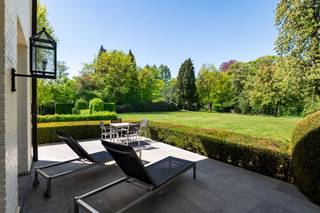 <p><span>Wonen in een groene oase zonder in te boeten aan comfort en bereikbaarheid. Ontdek deze karaktervolle, tijdloze en perfect onderhouden villa waar elegantie, licht en natuur harmonieus samenkomen. Dit eigendom onderscheidt zich door haar grote raampartijen die zorgen voor een zee van natuurlijk licht en een gevoel van openheid. Binnenstappen is thuiskomen in de grote en aangename leefruimtes, met zicht op de parktuin. De villa is gelegen op een perceel grond van ruim 1 ha met schitterend bomenbestand, aan een parallelwegje van de Bredabaan, tussen het centrum van Brasschaat en de Voshollei. </span></p><p><span> </span></p><p><span>Indeling</span></p><p><span>U betreedt de woning via de royale centrale inkomhal met gastentoilet en afzonderlijke vestiaire op stijlvolle natuurstenen vloer met trap naar de verdieping, en toegang tot drie verschillende leefruimtes met hoge plafonds en optimale lichtinval en openheid dankzij de talrijke royale raampartijen. De prachtige eiken parketvloer verleent deze vertrekken een tijdloze sereniteit. De gezellige woonkamer omvat een zitgedeelte aan de voorzijde van de villa met tv-hoek, en een tweede zitgedeelte met openhaard aan de achterzijde. Vervolgens is er toegang tot een stijlvolle eetkamer met tevens een prachtig uitzicht op de achtertuin. Vanuit deze eetkamer is er een doorgang naar een familyroom of bureau, eveneens met grote raamdeuren die uitgeven op het groen. Aan de voorzijde van de woning bevindt zich de leefkeuken, bestaande uit een functioneel ingerichte keuken en een ontbijthoek met toegang tot de voortuin. Vanuit de keuken hebt u ook toegang tot een volledige wasplaats of bijkeuken met mooie ingemaakte kasten en apart toilet met handenwasser, met aansluitend toegang tot de inpandige garages op gietvloer.</span></p><p><span> </span></p><p><span>Garage</span></p><p><span>De inpandige garage biedt plaats aan drie wagens, bevat een aparte bergplaats en is voorzien van automatische poorten.</span></p><p><span> </span></p><p><span>1e verdieping</span></p><p><span>Middels de ruime eiken trap in de inkomhal bereikt u de nachthal met licht en ruimte. Aan één zijde bevindt zich de mastersuite, bestaande uit een masterbedroom met zicht op de achtertuin, twee badkamers waarvan één badkamer met inloopregendouche, stijlvol lavabomeubel en toilet, en een andere badkamer met ligbad, lavabo en toilet, en een royale dressing met schitterende ingemaakte kasten. Een bijkomende kamer grenzend aan de mastersuite kan dienen als extra slaapkamer of hobbyruimte. </span></p><p><span>Aan de andere zijde van de nachthal bevinden zich nog twee ruime slaapkamers en een derde badkamer met ligbad en lavabomeubel. In de nachthal van deze zijde bevindt zich ook een apart toilet, alsook de toegang tot de diensttrap, die vertrekt vanuit de keuken en doorloopt tot de tweede verdieping.</span></p><p><span> </span></p><p><span>2e verdieping</span></p><p><span>Via deze diensttrap bereikt u de tweede verdieping, waar u een unieke meerwaarde vindt: een complete ruimte die perfect kan dienen als volwaardig appartement. Deze vertrekken kunnen naar wens worden ingericht als extra leefruimte, hobbykamer of bijkomende slaapkamers. Deze verdieping kan ook perfect gebruikt worden door bijvoorbeeld een inwonend familielid/ personeel/au-pair. Verschillende luiken op deze verdieping alsook één in de garage geven toegang tot de zolder.</span></p><p><span> </span></p><p><span>Kelder</span></p><p><span>De woning is helemaal onderkelderd en biedt o.m. bergruimtes, een wijnkelder, een waterverharder en een technische ruimte.</span></p><p><span> </span></p><p><span>Tuin en buitenruimtes</span></p><p><span>Het geheel biedt een mooie harmonie tussen binnen- en buitenleven dankzij de uitgestrekte zonneterrassen die uitnodigen om op elk moment van de dag te genieten van de rust en de groene omgeving. Met een prachtig terrein van ruim één hectare (ca. 10.337 m²) geniet u immers van een ongeëvenaard gevoel voor ruimte en privacy. Het pand is afgeschermd dankzij de privaatweg en een geluidsisolerende haag tussen die weg en de Bredabaan en beschikt over een royale oprit met automatische toegangspoort en ruime parkeergelegenheid. Een belangrijk kenmerk van dit eigendom is de fraaie omheinde parktuin, met waterloop aan de achterzijde. De tuin is smaakvol aangelegd met volwassen beplanting, tuinverlichting en wordt ook uitstekend onderhouden. Voorts is er een discreet gelegen tuinhuisje voor het tuin- en terrasmateriaal.</span></p><p><span> </span></p><p><span>Locatie / bijzonderheden</span></p><p><span>De ligging is enerzijds gunstig voor uitvalswegen en biedt een veilige omgeving met goede zichtbaarheid en sociale controle, en is anderzijds ideaal om met de fiets de voorzieningen binnen de wijk Vriesdonk te bereiken. De E19 ligt op slechts enkele minuten afstand, en de woning is centraal gelegen t.o.v. het openbaar vervoer en de dorpskern van Brasschaat. De afwerking van deze villa is het bewijs van een verfijnde, recente verbouwing met hoogwaardige materialen en oog voor detail. De woning beschikt over een doordachte indeling en ademt stijl en warmte uit. Mits enkele aanpassingen, zoals de eventuele vernieuwing van de keuken, kan dit eigendom beschouwd worden als een zeer exclusief object.</span></p><p><span> </span></p><p><span>Meer inlichtingen via ons kantoor.</span></p><p><span> </span></p>