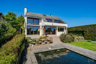 HULDENBERG – Nestled in a green and residential environment, this 310 m² detached villa (according to EPC) will charm lovers of light,...
