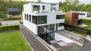 Sur une route d'accès, non loin de l'autoroute E313, nous trouvons ce magnifique bâtiment polyvalent avec de multiples possibilités. Actuellement, le rez-de-chaussée et le sous-sol sont utilisés comme atelier et espace d'exposition (391m²) et le 1er et le 2e étage comme logement avec bureaux (309m²).<br /><br />Disposition du rez-de-chaussée :<br />L'impressionnante façade vitrée avec la porte d'entrée nous mène à l'impressionnant espace d'exposition avec un plafond haut (3m), un sol en époxy, 2 salles de bains, un bureau séparé et à l'arrière une cuisine entièrement équipée, finie avec des armoires sur mesure du sol au plafond et une porte d'accès au parking/terrasse à l'arrière.<br /><br />Sous-sol :<br />Un escalier moderne nous mène à la deuxième partie de l'espace d'exposition. Grâce à une verrière à l'avant avec des carreaux de verre intégrés dans le sol du rez-de-chaussée et la grande baie vitrée à l'arrière, cet espace est baigné de lumière. Les portes en verre nous donnent accès à un large escalier menant au jardin/terrasse à l'arrière. À côté de cet espace, on trouve un grand espace de rangement/archives et une salle technique.<br /><br />Bureaux et logement au 1er étage :<br />En passant par la deuxième porte d'entrée à l'avant du bâtiment, on accède au hall d'entrée avec toilettes pour invités ainsi qu'à l'escalier et à l'ascenseur menant au premier étage. Cet espace ouvert a été compartimenté en 2 bureaux différents par des armoires et des cloisons en verre. Ensuite, on accède aux espaces de vie, avec parquet, de grandes fenêtres, un coin salon/télévision, une cheminée au gaz, la salle à manger et une cuisine entièrement équipée avec îlot de cuisson équipé d'une hotte encastrée, une plaque à induction, un Quooker, ainsi qu'un lave-vaisselle, un four, un four à micro-ondes, un four à vapeur à haute pression et une machine à café encastrée Miele. Ensuite, la grande buanderie/rangement avec notamment des refroidisseurs de vin Miele.<br /><br />2e étage :<br />Ici, nous trouvons une grande buanderie/salle de repassage, une petite cuisine avec accès à la très grande terrasse sur le toit, qui est également accessible depuis la chambre principale. Celle-ci dispose d'un dressing et d'une salle de bains avec 2 lavabos, des toilettes, une douche à l'italienne et un sauna. Le hall et la 2e chambre nous donnent accès à la 3e grande terrasse sur le toit (à l'arrière). Cette 2e chambre ou chambre d'amis dispose également d'une armoire encastrée et d'une salle de bains avec double lavabo, douche et toilettes.<br /><br />Caractéristiques :<br />- Finition haut de gamme<br />- Ascenseur disponible<br />- Panneaux solaires<br />- Magnifiques terrasses ensoleillées<br />- Box garage sur le terrain<br />- Possibilité de vivre et travailler<br />- Possibilité de cohabitation<br />- Extension possible grâce au terrain adjacent<br />- Certificat de performance énergétique A pour le commerce<br />- Certificat de performance énergétique A pour l'appartement<br /><br />L'achat supplémentaire du terrain adjacent est possible pour 260 000 €. On y trouve déjà un garage pour 3 voitures.