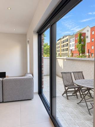 TE HUUR - GENT. Wonen in alle rust, vlak bij het hart van Gent? In het geliefde Prinsenhof vindt u deze stijlvolle nieuwbouwwoning met een prachtig uitzicht op het water. De woning is afgewerkt met kwaliteitsvolle materialen en biedt alle comfort voor wie aangenaam en zorgeloos wil wonen.<br /><br />Via het gezellige voortuintje komt u binnen in de inkomhal, waar een praktische vestiairekast en een gastentoilet voorzien zijn. De lichtrijke leefruimte voelt meteen ruim en uitnodigend aan, met een comfortabele zithoek en een royale plaats voor de eettafel. De open keuken met kookeiland is volledig ingericht en vormt het natuurlijke hart van de woning. Vanuit de leefruimte stapt u rechtstreeks het zonnige terras op. Een heerlijke plek om tot rust te komen en te genieten van het uitzicht op het water.<br /><br />Op de bovenverdieping bevinden zich drie volwaardige slaapkamers, een dressing, een afzonderlijk toilet en een moderne badkamer die stijl en comfort mooi combineert.<br /><br />Een bijzondere extra is het gemeenschappelijke binnenzwembad, waarvan de bewoners vrij gebruik kunnen maken. Zo geniet u thuis van een vleugje vakantiegevoel, het hele jaar door.<br /><br />Deze energiezuinige woning brengt rust, ruimte en hedendaags wooncomfort samen op een unieke locatie aan het water.<br /><br />De huurprijs bedraagt € 1.975 per maand, aangevuld met € 150 maandelijkse algemene kosten. Een staanplaats op het binnenplein kan worden bijgehuurd voor € 125 per maand.