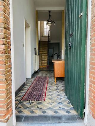 <br />In het hart van het idyllische Begijnhof van Turnhout, erkend als UNESCO Werelderfgoed, bevindt zich deze charmante en deels gerenoveerde woning in erfpacht. Een unieke kans voor wie houdt van historische architectuur, rust en een uitzonderlijk stukje erfgoed.<br />Bij binnenkomst word je verwelkomd door een brede gang die meteen het authentieke karakter van de woning benadrukt. Aansluitend vind je een ruime, gezellige woonkamer, waar de dubbele deuren zorgen voor een mooie lichtinval en directe toegang bieden tot het kleine, maar groene en intieme terras.<br />De ruime keuken vormt het hart van het gelijkvloers en biedt eveneens toegang tot het terras. Achter de keuken ligt een grote polyvalente ruimte met tal van mogelijkheden: atelier, hobbyruimte, thuiskantoor of extra leefruimte. Dankzij de hoogte kan hier zelfs een mezzanine worden ingericht. In deze ruimte bevinden zich ook een douche en lavabo, verder is er nog een apart toilet.<br />Op de bovenverdieping bevinden zich twee ruime slaapkamers en een te installeren badkamer. Alle materialen voor de plaatsing van een bad, lavabo en toilet zijn reeds aanwezig.<br />Tot slot beschikt de woning nog over een ruime, volledig te renoveren zolder die zich uitstekend leent voor extra bergruimte of een toekomstige uitbreiding.<br />Deze woning combineert historische charme met tal van mogelijkheden om er een comfortabele en persoonlijke thuis van te maken — allemaal op een werkelijk unieke, beschermde locatie.<br />Maandelijks te betalen kanon: 387 euro.