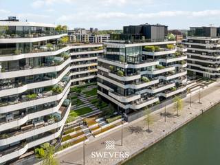 Voor meer info en foto’s, surf naar www.swevers.be – Dit recent appartement op de tweede verdieping van een verzorgde residentie (bouwjaar 2017) aan de Scheepvaartlaan in Hasselt combineert comfort met een moderne afwerking. Met een bewoonbare oppervlakte van 91 m² geniet je van een doordachte indeling en veel natuurlijk licht. De leefruimte van 23 m² vormt het hart van het appartement en sluit naadloos aan op het ruime terras van 28 m² met zicht op het kanaal. De open keuken (9,95 m²) is uitgerust met kwalitatieve toestellen van Miele en Bora en beschikt over een onderhoudsvriendelijk keramisch werkblad. Via de inkomhal bereik je het aparte toilet, een praktische berging met aansluitingen voor wasmachine en droogkast, en de centraal gelegen badkamer met inloopdouche en lavabo. De slaapkamer van 16 m² ligt rustig achteraan en geeft toegang tot een tweede terras van 4 m². Volgens het plan kan eenvoudig een tweede slaapkamer worden ingericht. Extra troeven zijn de kelderberging, ondergrondse fietsenstalling, gemeenschappelijke tuin en laadmogelijkheid voor elektrische wagens. De ligging is ideaal: op wandelafstand van winkels en horeca, nabij Quartier Bleu en het centrum, met vlotte verbindingen naar scholen, openbaar vervoer en snelwegen. Een autostaanplaats is apart aan te kopen voor €35.000. Voor meer informatie, bel 011 255 155. Bron bewoonbare oppervlakte: EPC – verslag.