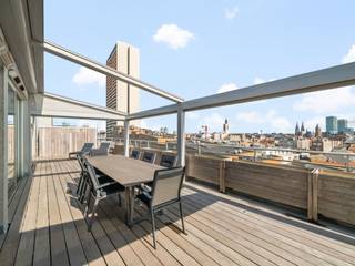 <p>Op de volledige achtste verdieping, in het hart van Oostende, bevindt zich dit architecturaal uitgewerkte penthouse van circa 225 m². Royale ruimtes, een hoogwaardige afwerking en een open uitzicht over de stad geven het appartement het karakter van een volwaardige woning - maar dan in de lucht.</p>
<p>Het zonnige terras strekt zich uit over een oppervlakte van maar liefst 90 m² en biedt een weids uitzicht over Oostende. Dankzij de Renson-constructie kan een gedeelte volledig of gedeeltelijk worden afgesloten. Zo zit u beschut tegen de wind, zonder het zicht te verliezen, en geniet u van de buitenruimte bij uiteenlopende weersomstandigheden. Aan de achterzijde bevinden zich nog twee bijkomende terrassen.</p>
<p>Binnen bepalen licht, ruimte en maatwerk de sfeer. De grote raampartijen brengen overvloedig daglicht binnen en versterken het open gevoel. De bijzonder ruime leefruimte biedt moeiteloos plaats aan een salon, eetkamer en afzonderlijke bureauhoek. De open keuken met kookeiland en kwalitatieve toestellen sluit hier naadloos op aan.</p>
<p>Doorheen het appartement vormen de parketvloeren, indirecte verlichting en talrijke ingebouwde kasten een verzorgd en samenhangend geheel. Het maatwerk is niet alleen esthetisch sterk, maar zorgt ook voor uitzonderlijk veel praktische bergruimte.</p>
<p>De master bedroom beschikt over een eigen dressing, een luxueuze badkamer met ligbad en inloopdouche en rechtstreekse toegang tot het terras. Daarnaast zijn er nog twee volwaardige slaapkamers en een tweede badkamer. Vloerverwarming en de aanwezige voorziening voor airconditioning vervolledigen het wooncomfort.</p>
<p>De ligging combineert openheid en privacy met alle voordelen van het stadscentrum. Het Casino-Kursaal, de Zeedijk, winkels, restaurants en culturele voorzieningen bevinden zich op wandelafstand. Er is eveneens de mogelijkheid om parkeerplaatsen afzonderlijk aan te kopen.</p>
<p><strong>Troeven van dit appartement:</strong></p>
<ul>
<li>
<p>De volledige achtste verdieping met circa 225 m² woonoppervlakte</p>
</li>
<li>
<p>Zonnig terras van 22 meter met open zicht over Oostende</p>
</li>
<li>
<p>Afsluitbare Renson-constructie voor beschut buitenleven</p>
</li>
<li>
<p>Architecturale inrichting met doorgedreven maatwerk</p>
</li>
<li>
<p>Drie volwaardige slaapkamers en twee badkamers</p>
</li>
<li>
<p>Centrale ligging vlak bij het Casino-Kursaal en de Zeedijk</p>
</li>
</ul>