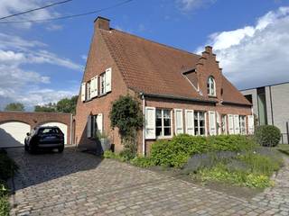 YES! Voor dit pand kan je zélf een afspraak inboeken! Ga naar de advertentie op onze website www.justwonen.be en plan meteen je afspraak in.<br /><br />Landelijk wonen in Oud-Turnhout.<br /><br />Jawel, dat mag je letterlijk nemen. Niet enkel woon je in het rustige Oosthoven, maar je zit in dit geval ook letterlijk naast natuurgebied. Sterker nog, je kan ervan genieten vanuit je achtertuin. Heerlijk, toch?<br /><br />Maar ook de woning is lekker landelijk. Niet strak en kil, maar warm en cosy. En vergis je niet: “landelijk” hoeft geen synoniem te zijn voor “ouderwets”. Oké, de inrichting op dit moment is wat klassieker – wat prima is – maar denk er even wat eigentijdse meubels bij, en het krijgt meteen al een heel andere sfeer.<br /><br />Indeling:<br />Een inkomhal zoals ’t vroeger was: groot, praktisch en met een tikje grandeur. Naast de inkomhal vind je alvast een eerste kamer, momenteel ingericht als kantoor. <br /><br />Verder heb je vanuit de hal ook toegang naar de woonkamer en keuken. Zullen we eerst in de woonkamer starten? Die is groot, dus méér dan voldoende ruimte voor een gezellige woon- en eetkamer. Het kleine trapje tussen beide ruimtes zorgen voor een subtiele overgang. <br /><br />Om de hoek vinden we de keuken. En je ziet het al: deze kreeg al een flinke make-over. En da’s dus wat we bedoelen: met wat eigentijdse, hippe materialen krijg je al meteen een hele hedendaagse sfeer. De keuken werd hoogwaardig afgewerkt, en voorzien van alle snufjes. <br /><br />Aan de achterzijde van het huis zit een bergplaats, een grote wasplaats en apart toilet. Verder is ook de badkamer beneden. Deze is misschien een tikje basic, maar netjes en dus prima in orde. <br /><br />Boven zijn 4 slaapkamers, en nog een 5de kamertje als opslag of een kleine bureau. Ook hier vinden we heel wat extra opberghoekjes voor de rommeltjes die je liever niet in ’t zicht hebt. Tenslotte is ook hier nog een apart toilet.<br /><br />De tuin is nog een work in progress, maar de foto’s (visuals) laten alvast zien hoe het er straks uit gaat zien: een groot terras met gezellige overkapping, een buitendouche (jawel!) en een stukje gazon. En dan misschien nog wel ’t beste van allemaal: een heerlijk uitzicht over de weilanden en ’t groen. Tenslotte heb je nog een dubbele garage voor je auto’s.<br /><br />Een huis waar je lekker oldskool kan thuiskomen.