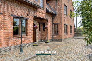 In een rustige en residentiële buurt nabij het centrum van Peizegem bevindt zich deze ruime en perfect onderhouden gezinswoning op een perceel van maar liefst 9a67ca. De woning geniet van een hoge mate van privacy, een prachtig open zicht achteraan en een ideale ligging op een steenworp van Buggenhoutbos.Indeling- Gelijkvloers: U wordt verwelkomd in een ruime inkomhal met gastentoilet. De lichtrijke leefruimte geniet dankzij de grote raampartijen van een aangename connectie met de tuin en het omliggende groen. Aansluitend bevindt zich een bijzonder ruime, high end leefkeuken met eethoek. Verder beschikt het gelijkvloers over een bureau, een polyvalente ruimte met tal van mogelijkheden (praktijk, kantoor, hobbyruimte, vrij beroep, ...) en een badkamer. Het volledige gelijkvloers werd grondig gerenoveerd in 2004.- Eerste verdieping: Via de nachthal bereikt u vier ruime slaapkamers, afgewerkt met stijlvolle parketvloeren. Daarnaast vindt u hier een afzonderlijk toilet. - Ruime zolder, te bereiken via valtrap- Buitenruimte: De mooi aangelegde tuin vormt een oase van rust en privacy. Op het ruime terras geniet u volop van het zicht op het achterliggende groen. Een grote garage met praktische zolderverdieping biedt extra opslag- en werkruimte. De oprit biedt plaats voor verschillende wagens. Karakteristieken- Bewoonbare oppervlakte: ca. 320 m²- Uitstekende staat van onderhoud- Pelletkachel van het merk Piazzetta- 22 zonnepanelen, met groenestroomcertificaten geldig tot eind 2029- Aangelegde tuin met ruim terras- Vrij vanaf 15/01/2027- Maatregelen in het maatregelenregister: neeBent u op zoek naar een ruime, instapklare woning met karakter, privacy en tal van mogelijkheden voor wonen én werken? Dan is deze unieke eigendom in Peizegem absoluut een bezoek waard. Contacteer ons vandaag nog via 02 460 80 46 of info@structura.be voor meer informatie of een persoonlijke rondleiding en ontdek zelf de troeven van deze uitzonderlijke woning.
