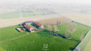 Via een karaktervolle dreef, omzoomd door statige bomen, bereikt u deze uitzonderlijke erfgoedhoeve, prachtig gelegen te midden van uitgestrekte velden en natuur. Een zeldzame opportuniteit voor wie op zoek is naar een plek met ziel en geschiedenis.<br />De hoeve is opgebouwd rond een open binnenplaats en omvat de zuidelijk gerichte hoofdwoning met meerdere bijgebouwen, harmonieus ingeplant in het groen. De robuuste bakstenen constructies, de typische dakpannen en de landelijke architectuur zorgen voor een tijdloos en sfeervol geheel. Aanpalend bevinden zich diverse bijgebouwen, stille getuigen van het ambachtelijke verleden van deze site.<br />Binnenin biedt de te renoveren woning een functionele indeling met op het gelijkvloers een inkomhal die toegang geeft tot de zit- en leefruimte met open zicht op de binnenplaats, een keuken, twee kelders en twee polyvalente ruimtes die naar wens kunnen worden ingericht. De “volte kamers” benadrukken het authentieke karakter van de woning. Op de verdieping bevindt zich een ruime open zolder met grote mazouttank, aangevuld met twee kamers en twee trappen die zorgen voor een praktische verbinding met het gelijkvloers.<br />Deze eigendom maakt deel uit van het bouwkundig erfgoed en kent een rijke geschiedenis als voormalige openlucht steenbakkerij. Dit verleden verklaart de uitzonderlijk hoge gebouwen opgetrokken uit ‘eigen’ bakstenen alsook de specifieke landschappelijke kenmerken, zoals de lager gelegen gronden en het aanwezige waterreservoir(vijver). De hoge bijgebouwen met dubbele bouwlaag versterken bovendien het potentieel voor diverse invullingen. De eerste strook landbouwgrond (momenteel maïsland), gelegen tussen de schuur en de straat, kan afzonderlijk worden bijgekocht.<br />De hoeve wordt momenteel verwarmd op mazout. De riolering verloopt richting de omliggende weilanden.<br />Wenst u een bezoek ter plaatse of info betreft de eventuele herbestemming? Neem vrijblijvend contact op met maggie@vastgoednorman.be of 0479402404.