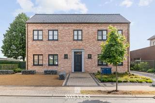 Voor meer info en foto’s, surf naar www.swevers.be – Deze instapklare open bebouwing in de Volksstraat 28A in Diepenbeek biedt uitzonderlijk veel ruimte, comfort en flexibiliteit. De woning werd ingericht als kangoeroewoning met twee volwaardige wooneenheden, aparte meters en meerdere toegangen. Ideaal voor grote gezinnen, samenwonen met familie, verhuren of investeren met extra rendement. Het pand werd gebouwd in 2003, goed onderhouden en beschikt over ca. 307 m² bewoonbare oppervlakte. Op het gelijkvloers vindt u een ruime leefruimte, praktische keuken met aansluiting naar de lichtrijke veranda, drie slaapkamers, een vernieuwde badkamer met dubbele wastafel en ligbad, apart toilet en berging. Op de verdieping bevindt zich een volwaardig appartement dat momenteel verhuurd wordt. Dit omvat een lichtrijke leefruimte, keuken, twee slaapkamers, badkamer, apart toilet en een ruim terras van ca. 26 m². Buiten geniet u van een perceel van 17 are 58ca met zuidwestelijke oriëntatie, overdekt terras en open zicht op agrarisch gebied. Verder beschikt de woning over twee inpandige garages van samen ca. 90 m², een carport, rolluiken en zonnepanelen. De ligging is rustig, maar toch dicht bij scholen, winkels, openbaar vervoer en belangrijke verbindingswegen. Een veelzijdige eigendom met tal van mogelijkheden. Voor meer informatie, bel 011 255 155. Bron bewoonbare oppervlakte: EPC – verslag.