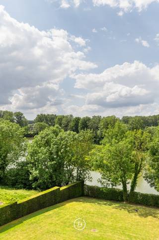 Op een toplocatie in Sint-Pieters-Leeuw bevindt zich dit uitzonderlijke penthouse met fantastische vergezichten over een natuurgebied en vijvers. Het penthouse met een hoge afwerkingsgraad werd afgewerkt met kwalitatieve materialen en maatwerk, waaronder parket, airconditioning, een centraal stofzuigsysteem en een zonnetenten.<br /><br />Het penthouse is als volgt ingedeeld: <br />Via de lift die gaat tot de private inkomhal, kom je terecht in de lichtrijke leefruimte met aparte tv-hoek, deze sluit via grote schuiframen naadloos aan op het ruime terras. De hypergeïnstalleerde keuken met aansluitende berging en wasruimte biedt alle hedendaags comfort. De master suite beschikt over een inloopdressing en een ensuite badkamer, terwijl de tweede slaapkamer een eigen douchekamer heeft. Een afzonderlijk bureau vervolledigt het gelijkvloerse woonniveau.<br /><br />Op de bovenverdieping bevindt zich een polyvalente ruimte die dienst kan doen als extra slaapkamer of bureauruimte, met berging en een indrukwekkend, rondom gelegen dakterras met buitendouche.<br /><br />Een extra troef is een afzonderlijke ruimte van 77 m² op het gelijkvloers. Deze ruimte biedt tal van mogelijkheden zoals een afzonderlijke kantoor- of praktijkruimte, een appartement voor een au-pair of als kangoeroewoning. Verder beschikt deze ruimte over zicht op de tuin, een eigen terras en een privatieve buitenparking. <br /><br />Tot slot beschikt deze unieke eigendom over een dubbele ondergrondse garage en drie private kelderbergingen, waaronder een wijnkelder.
