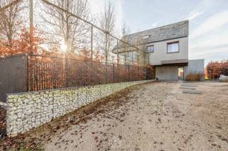 Deze eigendom is gewoonweg een parel in zijn soort en scoort hoog op <strong>woonbeleving door zijn concept</strong>, de open ruimteperspectieven en gebruik van <strong>beton op zijn best in combinatie met warme houttinten</strong>. De woning heeft tegelijk een <strong>brutalistisch en minimalistisch karakter</strong>. Betonnen prefab elementen geven aan de binnenkant van het huis prachtige kleurschakeringen. Het huis werd bewust met tijdloze en sobere materialen gebouwd waardoor ook eventuele designobjecten mooi tot hun recht kunnen komen.<br /><br />Je komt de woning binnen via een inkomhal met afzonderlijk toilet en toegang tot de berging. Dit afzonderlijk toilet kan zowel gebruikt worden via de inkomhal als de praktijkruimte.<br />Vanuit de inkom kom je in de woonkamer waar licht en ruimte de tuin laten binnenkomen.<br />De eetkamer en keuken staan in verbinding met het ruime terras en de tuin. Op het gelijkvloers is een <strong>ruime praktijkruimte van +/-50m²</strong> dat kan ingezet worden als kantoor, kinesistenpraktijk of polyvalente ruimte. Op de eerste verdieping is een bureauruimte met een heel fijn zicht op de voortuin en de benedenverdieping, twee slaapkamers, een ruime wasplaats, een badkamer (met ligbad, douche en toilet). Op de tweede verdieping is een zolderruimte, technische ruimte, een bijkomende derde slaapkamer en een ruime zolderkamer die eveneens kan ingericht worden naar eigen wensen.<br /><br />Bijkomende troeven:<br />- <strong>EPC label A ! </strong><br />- voldoende parkeerplaats<br />- architecturaal interessante woning<br />- multifunctioneel karakter en inzetbaarheid gezien uitzonderlijke praktijkruimte<br /><br />Aarzel niet om een bezoek aan te vragen via vastgoed@claves.be of het nummer 03/5029874<br /><br /> 