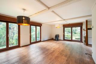 Maison individuelle sur un terrain d'environ 894 m². La maison offre 4 chambres, deux salles de bains et un agréable jardin orienté au sud-ouest avec beaucoup d'intimité. Une base idéale pour ceux qui souhaitent rénover et moderniser la maison selon leurs goûts.<br /><br />Rez-de-chaussée:<br />Le hall d'entrée donne accès aux différentes pièces et à l'escalier menant à l'étage.<br /><br />Le salon forme un espace ouvert et spacieux avec de la place pour un coin salon et un coin repas. De grandes baies vitrées apportent beaucoup de lumière naturelle et créent un agréable contact avec la nature environnante. Un poêle à bois apporte une touche supplémentaire dans le coin salon.<br /><br />La cuisine, actuellement traditionnelle, est adjacente au salon. La disposition actuelle se prête parfaitement à une utilisation plus ouverte et contemporaine, permettant de mieux relier la cuisine, la salle à manger et le jardin.<br /><br />Le rez-de-chaussée comprend également plusieurs pièces pouvant être utilisées de manière flexible comme chambre à coucher, bureau ou espace de loisirs, ainsi qu'une salle de bains avec baignoire/douche et double lavabo. Un débarras pratique complète cet étage.<br /><br />Premier étage:<br />L'escalier en bois mène à un palier spacieux et lumineux avec fenêtre de toit. À cet étage se trouvent 2 chambres supplémentaires et des espaces polyvalents. Une deuxième salle de bains avec douche et lavabo est également présente. Un grand espace de rangement intégré et séparé offre un espace de stockage supplémentaire.<br /><br />Au total, la maison dispose de 4 chambres et 2 salles de bains, offrant des possibilités intéressantes pour une famille ou pour une combinaison de vie et de travail à domicile.<br /><br />Jardin:<br />La maison est entourée d'un jardin mature avec un caractère verdoyant prononcé. Le jardin arrière est orienté au sud-ouest.<br /><br />Détails:<br />- 4 chambres et 2 salles de bains<br />- Jardin orienté au sud-ouest<br />- PEB B - 196 kWh/(m² an)<br />- À moderniser/rénover avec des possibilités de réaménagement intéressantes principalement grâce aux murs extérieurs solides.