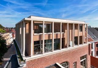 <p><em><strong>Wonen op het hoogste niveau, midden in Turnhout.</strong></em></p>
<p><strong><em>Een volledige verdieping voor uzelf, met Turnhout aan uw voeten.</em></strong></p>
<p><span>Dit penthouse beslaat de volledige derde verdieping van het monumentale Huize Boone-Misonne. Op 161 m² geniet u van royale woonruimte, licht en een uitzonderlijk gevoel van privacy, op een adres waar meer dan een eeuw geschiedenis samenkomt met hedendaags wooncomfort.</span></p>
<p><span>De lift brengt u rechtstreeks naar uw eigen verdieping. Een ruime inkomhal met vestiaire en gastentoilet vormt een uitnodigende ontvangst. Grote raampartijen aan drie gevelzijden trekken het daglicht diep naar binnen en openen het zicht over de stad.</span></p>
<p><span>De leefruimte biedt alle ruimte om te koken, te tafelen en tot rust te komen. Keuken, eetkamer en zithoek vloeien in elkaar over, met telkens dat weidse uitzicht als achtergrond. Via het grote schuifraam bereikt u het westgerichte terras van 27 m², met een praktische buitenberging. Hier krijgen lange lunches en ontspannen avonden vanzelf hun plek, met zicht op drie kerktorens, de Turnova-toren en een verrassend groene skyline.</span></p>
<p><span>De master suite beschikt over een eigen badkamer met inloopdouche en een afzonderlijk toilet. De twee overige slaapkamers maken gebruik van de tweede badkamer: ideaal voor familie, logés of een combinatie van slapen en werken. Een aparte was- en technische ruimte houdt de dagelijkse praktische zaken discreet uit het zicht.</span></p>
<p><span>Een ruime private kelderberging kan afzonderlijk worden aangekocht. Voor wijnliefhebbers is bovendien de historische gewelfde wijnkelder beschikbaar: een bijzonder verlengstuk van dit karaktervolle adres. Ook twee carports zijn optioneel aan te kopen, afzonderlijk of samen.</span></p>
<p><strong><span>Een beschermd monument met een nieuw hoofdstuk</span></strong></p>
<p><span>Huize Boone-Misonne behoort tot de meest markante herenhuizen van Turnhout. Architect L. Van Ravestyn ontwierp het aan het begin van de twintigste eeuw. Met respect voor zijn rijke verleden werd het gebouw gerestaureerd tot een exclusieve residentie met slechts vijf appartementen en drie kantoorruimtes.</span></p>
<p><span>In de historische delen van het gebouw leeft het oorspronkelijke karakter voort in witmarmeren vloeren, sierlijke stucplafonds, de indrukwekkende eiken trap, glas-in-loodramen en authentiek houten buitenschrijnwerk.</span></p>
<p><span>Onder het toeziend oog van Erfgoed Noorderkempen werd dit erfgoed gecombineerd met hedendaagse technieken: een individuele warmtepomp, vloerverwarming en -koeling, ventilatiesysteem D, zonnepanelen, hoogrendementsbeglazing en doorgedreven isolatie. Het beoogde energielabel is A.</span></p>
<p><strong><span>Volledig afgewerkt, met een keuken op uw maat</span></strong></p>
<p><span>Het gebouw is klaar voor oplevering en de eerste bewoners hebben hun intrek al genomen. De residentie beschikt over een afgesloten parking met carports en buitenstaanplaatsen, een ondergrondse fietsenstalling en private kelderbergingen.</span></p>
<p><span>Het penthouse is volledig afgewerkt, met uitzondering van de keuken. Hiervoor is een ruim budget voorzien, zodat u de inrichting naar uw eigen smaak kunt laten realiseren. Zo geeft u het hart van uw nieuwe thuis een persoonlijke invulling.</span></p>
<p><strong><span>Aankopen onder registratierechten</span></strong></p>
<p><span>De verkoop gebeurt onder het stelsel van registratierechten, zonder btw op de vraagprijs. Afhankelijk van uw persoonlijke situatie en de toepasselijke voorwaarden bedraagt het tarief 2% of 12%.</span></p>
<p><em><strong>Een volledige verdieping, een bijzonder uitzicht en een adres met geschiedenis. Ontdek het penthouse van Huize Boone-Misonne tijdens een persoonlijk plaatsbezoek.</strong></em></p>