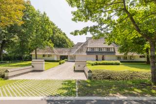 In het hart van het prestigieuze Scheutbos – een van de meest gegeerde locaties van Vlaanderen – bevindt zich deze unieke, rietgedekte villa uit 2000. Met een woonoppervlakte van maar liefst 500 m² op een riant hoekperceel van 5.529 m², biedt deze eigendom een uitzonderlijke combinatie van rust, ruimte en klasse. Deze villa in landelijke stijl ademt authenticiteit, terwijl ze moeiteloos voldoet aan de hoogste hedendaagse comfortnormen. De royale inkomhal verwelkomt u met een warme elegantie en beschikt over een vestiaire en gastentoilet. De ruime living met imposante glaspartijen baadt in natuurlijk licht en biedt een panoramisch zicht op de groene tuin. De open keuken met kookeiland vormt het kloppend hart van het huis, naadloos verbonden met een ruime eetplaats – perfect voor stijlvolle diners en gezellige familiemomenten. De woning beschikt over vijf volwaardige slaapkamers en twee smaakvol afgewerkte badkamers, waardoor zowel privacy als comfort verzekerd zijn. Een praktische wasplaats verhoogt het dagelijkse gemak, terwijl de inpandige garage ruimte biedt aan twee wagens – met bovendien extra parkeergelegenheid op het perceel zelf. Het bijgebouw biedt tal van mogelijkheden: van praktijkruimte voor vrije beroepen tot een atelier, gastenverblijf of hobbyruimte. Wilt u wonen in een oase van rust met vlotte verbindingen en alle luxe binnen handbereik? Dan is dit unieke pand in Scheutbos uw ultieme droomwoning. De woning wordt gedeeltelijk gemeubeld verhuurd. EPC 257 kWh/m2