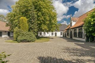 This exceptional domain is located a stone's throw from Roeselare's Grote Markt (only 2.5 km from a birds-eye view) and has an easy connection to the E403. For those looking for space, greenery, peace and lots of character, this is an excellent opportunity.This exclusive property includes a stately villa in castle farm style (built in 1976), a separate caretaker's house (approx. 201 m² living area) and various outbuildings, including stables and a party room. The villa has a generous living area of 683 m² and exudes rural elegance that immediately charms.Architectural elegance with romantic flair:white facades, elegant skylights, arched passageways, wrought iron ornaments, a massive wooden entrance door and characterful stained glass windows provide an authentic look with grandeur. The central tower acts as an architectural eye-catcher.Inside, the house offers, among other things:an impressive entrance hall with a long corridor | spacious living room with a view of the park garden | an office room and bedrooms on the ground floor | a kitchen with adjoining utility room | single-storey bathroom and solarium | multiple (bed) rooms on the first floor | a wine cellar and double garage...Outdoor life in a park garden with a pondThe living areas overlook the large pond and the surrounding park grounds, providing a permanent vacation feeling. The courtyard, surrounded by the buildings, garden wall and gateway, offers absolute privacy and a special atmospheric experience.Versatility and potentialThe caretaker's house is currently rented but will be vacant soon. The domain can be divided; buying with more or less land is negotiable. In addition, several spacious plots of land (recently parceled) border the whole, which are available separately for separate sale.A property with a soulThe presence of ancient antique architectural elements gives this villa an exceptional appearance. A unique property with countless options: ideal for refreshing or redeveloping into a luxurious private residence, combined living and working, space for horses or other animals, storage, and much more.Contact us for more info or a visit. You should experience this domain on site.