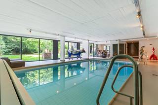 Exclusief wonen op een uitstekende locatie in Berchem!<br /><br />Vanaf de elegante inkomhal – uitgerust met een vestiaire en afzonderlijk gastentoilet – komt u binnen in de indrukwekkende leefruimte. De warme parketvloer en gezellige open haard creëren een uitnodigende sfeer, terwijl de uitzonderlijke gevelbreedte en grote raampartijen zorgen voor een overvloed aan natuurlijk licht en een prachtig zicht op de weelderige, privatieve stadstuin. Deze veelzijdige ruimte biedt moeiteloos plaats aan een eetgedeelte, een werkhoek en meerdere zithoeken die u geheel naar eigen wens kunt inrichten.<br /><br />De strak vormgegeven keuken is uitgerust met hoogwaardige Smeg-apparatuur, waaronder een vijfpits gasfornuis, grill, friteuse, oven, stoomoven, microgolf, vaatwasser, koelkast en diepvriezer – perfect voor wie graag kookt in stijl. Het centrale kookeiland met inox werkblad, de overvloed aan opbergruimte en de charmante ontbijthoek maken van deze keuken niet alleen een functionele, maar ook een visuele troef in de woning.<br /><br />Via de nachthal, eveneens afgewerkt met een elegante parketvloer, bereikt u het slaapgedeelte. De ruime masterbedroom beschikt over een ensuite dressing en een luxueuze badkamer met inloop regendouche, ligbad, handdoekdroger en een stijlvol meubel met dubbele wastafel. Verder zijn er nog 2 volwaardige slaapkamers op parket, evenals een 2de badkamer met inloopdouche, wastafel en toilet.<br /><br />Private wellnessruimte, bereikbaar met een eigen lift. Hier geniet u van een binnenzwembad, sauna, inloopdouche, hammam, apart toilet en een uitgeruste fitnessruimte. Dankzij de volledig schuifbare ramen naar de tuin loopt deze ontspanningsruimte naadloos over in het buitenleven, wat zorgt voor een gevoel van rust en vrijheid.<br /><br />Een ruime garage met automatische poort voor 2 wagens en waar ook nog een berging aanwezig.