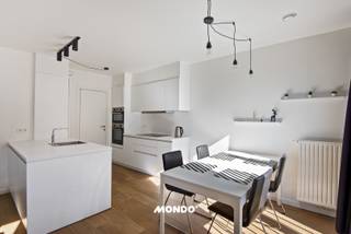 Op de eerste verdieping van dit recente appartementsgebouw (bouwjaar 2022) bevindt zich dit energiezuinige en perfect instapklare appartement. Een ideale woonst voor wie comfort, licht en modern woonplezier zoekt.<br />Via de inkomhal betreed je het appartement. Aan de linkerzijde kom je in de ruime en lichtrijke leefruimte met gezellige living, eetplaats en een open, volledig geïntegreerde keuken. Aansluitend is er een praktische berging, ideaal voor extra opslagruimte en perfect geschikt als was- en droogruimte.<br /><br />Een absolute troef is het zuidgericht terras, dat toegankelijk is vanuit de leefruimte én beide volwaardige slaapkamers. Hier geniet je de hele dag van zon en rust. Ideaal om te ontspannen of gezellig te tafelen.<br /><br />Verder beschikt het appartement over:<br />- 2 volwaardige slaapkamers<br />- Een apart gastentoilet<br />- Een moderne badkamer met dubbele lavabo en inloopdouche<br />- Een extra aparte berging voor bijkomende opslag<br /><br />Dankzij de recente bouw en de doordachte, praktische indeling geniet je hier van hedendaags wooncomfort in een energiezuinige setting.<br /><br />Interesse? Maak snel een afspraak en kom zelf de sfeer en het comfort van dit appartement ervaren tijdens een bezoekmoment.<br /><br />Contacteer: Marte Van Damme <br />marte@mondovastgoed.be<br />tel: 0498 40 40 50