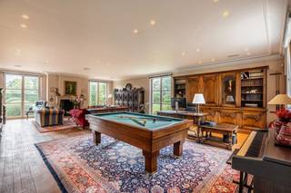 <span><strong>Verscholen in het groen van Beerse bevindt zich dit karaktervolle landgoed op een prachtig aangelegd domein van ca. 1,78 hectare. De woning werd doordacht ingedeeld en combineert royale leefruimtes met een afzonderlijke mastersuite, een kinder- en gastengedeelte, een bureau met eigen inkom en een uitgebreide wellness- en fitnessruimte. Ook buiten werd niets aan het toeval overgelaten. Een aangelegde tuin met vijver, boomgaard en irrigatiesysteem vormt samen met de gedraineerde paardenpiste, de volledig uitgeruste stal met vier paardenboxen en het zwembad een uitzonderlijk geheel.</strong> </span><br />
<p><span>Indeling</span><br />U komt binnen in de centrale hal. De leefruimtes vormen het hart van de woning, verschillende salons, een ruime leefkeuken en een authentieke wijnkelder creëren een warme en uitnodigende sfeer. Op de verdieping bevindt zich de volledige mastersuite, ingericht met een ruime slaapkamer, dressing en badkamer.</p>
<p>Via de centrale doorgang bereikt u het tweede gedeelte van de woning. Hier bevinden zich een bureau met een eigen inkom, een apart toilet en douche, waardoor deze ruimte zich eveneens uitstekend leent als logeerkamer of praktijkruimte. Verder vindt u hier de fitness en een volledig uitgeruste wellnessruimte met sauna, hammam en stortbad.</p>
<p>Op de verdieping bevinden zich vier slaapkamers. Telkens twee kamers delen een badkamer met elks een eigen deur, wat zorgt voor een praktische indeling die perfect aansluit bij een gezinswoning.</p>
<p>Ook buiten komt dit eigendom volledig tot haar recht. De tuin werd met veel zorg aangelegd en beschikt over een sierlijke vijver, een boomgaard met onder meer appel-, peren- en kersenbomen en een automatisch irrigatiesysteem dat het volledige domein bedient. Voor paardenliefhebbers is er een gedraineerde paardenpiste met een aansluitende stal, voorzien van vier paardenboxen en alle nodige faciliteiten. Het zwembad is momenteel buiten gebruik, maar biedt de mogelijkheid om opnieuw als zwembad in gebruik te worden genomen.<br /><br /><span>Bijzonderheden<br /></span>- Karaktervol landgoed op een aangelegd domein van ca. 1,78 hectare<br />- Doordachte indeling met afzonderlijke mastersuite en kinder-/gastengedeelte<br />- Bureau met eigen inkom, ideaal voor een vrij beroep of praktijk aan huis<br />- Fitnessruimte en wellness met sauna, hammam en stortbad<br />- Authentieke wijnkelder<br />- Gedraineerde paardenpiste met volledig uitgeruste stal voorzien van vier paardenboxen<br />- Aangelegde tuin met vijver en boomgaard<br />- Automatisch irrigatiesysteem over het volledige domein<br />- Zwembad met mogelijkheid tot heringebruikname<br />- EPC label C<br /><br />Voor de virtuele tour: https://visithome.ai/fCDZmFpfGedg7Ljk4U83Jp?mu=m</p>