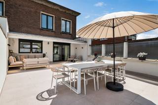 <p><span>Deze statige voormalige dokterswoning combineert grandeur, ruimte en hedendaags wooncomfort op een uitzonderlijke manier. De woning werd recent volledig gerenoveerd en biedt tal van mogelijkheden voor grote gezinnen, een kangoeroewoning of het combineren van wonen en werken.</span></p><p><span>Op het gelijkvloers bevindt zich een volledig afzonderlijk woongedeelte, ideaal voor inwonende ouders, kinderen of gasten. Dit private gedeelte beschikt over een eigen keuken, een gezellige leefruimte, twee slaapkamers en een gastentoilet. Aansluitend vindt u een ruime polyvalente ruimte die perfect kan dienen als hobbyruimte, praktijkruimte, atelier of opslagplaats. Deze ruimte bevindt zich naast de dubbele inpandige garage.</span></p><p><span>De volledige woning is bovendien onderkelderd, wat zorgt voor een enorme hoeveelheid extra bergruimte en tal van mogelijkheden.</span></p><p><span>Vanaf de eerste verdieping start de hoofdwoning. Hier wordt u onmiddellijk verwelkomd door een indrukwekkende leefruimte met prachtige hoge plafonds en een stijlvolle parketvloer die de authentieke charme van de woning perfect in de verf zet.</span></p><p><span>Achter de living bevindt zich de luxueuze leefkeuken, uitgerust met een royaal kookeiland en voorzien van alle moderne toestellen. De ingebouwde koelkast met geïntegreerd ledscherm vormt een echte blikvanger. Via het grote schuifraam heeft u rechtstreeks toegang tot het ruime dakterras met westelijke oriëntatie, waar u elke avond kunt genieten van een prachtige zonsondergang. Op deze verdieping bevindt zich eveneens een tweede gastentoilet.</span></p><p><span>De tweede verdieping biedt alle comfort voor het moderne gezin. Er is een praktische wasruimte voorzien voor wasmachine en droogkast, evenals een ruime badkamer uitgerust met een ligbad, douche en toilet. Aan de voorzijde van de woning bevinden zich drie ruime slaapkamers, terwijl aan de zijgevel de royale master bedroom is gelegen. Deze beschikt over een eigen en suite badkamer met dubbele lavabo, ligbad en toilet.</span></p><p><span>Verder werd de woning uitgerust met nieuwe aluminium ramen en automatische rolluiken aan alle ramen, wat zorgt voor extra comfort, veiligheid en energiezuinigheid.</span></p><p><span>De woning is gelegen nabij het Jan Palfijn ziekenhuis.</span></p>