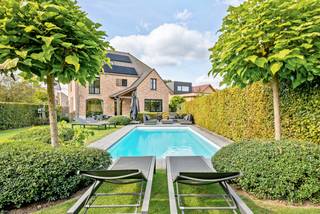 Dans le quartier prisé de Sint-Lambrechts-Herk se trouve cette magnifique et exceptionnelle villa où le confort, le luxe et l'habitat économe en énergie se rencontrent. Avec une superficie de terrain de 900 m² et une superficie habitable de 368 m², cette maison offre un confort de vie exceptionnel pour toute la famille. <br /><br />Sur le plan énergétique, cette maison obtient un excellent score avec un label EPC A. Des panneaux solaires, une batterie domestique, une borne de recharge pour voitures électriques et un système de ventilation de type D contribuent à une expérience de vie économe en énergie et tournée vers l'avenir.<br /><br />Source de la superficie habitable : EPC<br /><br />Disposition du rez-de-chaussée :<br />En entrant dans la maison, le hall d'entrée vous accueille avec un toilette invité et un vestiaire. De là, vous accédez à un espace de vie particulièrement convivial et lumineux, où de grandes fenêtres offrent une vue magnifique sur la terrasse et le jardin. La cheminée en bois chaleureuse et la hauteur de plafond impressionnante de 2,8 mètres renforcent la sensation d'espace et de chaleur.<br /><br />Atteignant directement l'espace de vie se trouve la cuisine entièrement équipée, où la qualité et la fonctionnalité sont au cœur des préoccupations. La cuisinière La Cornue au caractère unique et le plan de travail en pierre bleue font de cette cuisine un véritable point focal. De plus, le rez-de-chaussée dispose d'une grande buanderie, d'un garage pratique et d'un bureau séparé qui communique directement avec l'espace de vie et peut être fermé en toute tranquillité grâce aux portes en chêne massif.<br /><br />Disposition des étages :<br />Au premier étage se trouvent trois grandes chambres. La chambre principale dispose de sa propre salle de bains attenante et d'un dressing, ce qui ajoute une touche supplémentaire de luxe et d'intimité. De plus, il y a une deuxième salle de bains, équipée d'une douche et de deux lavabos.<br /><br />Un atout indéniable est le vaste grenier aménagé, accessible par un escalier fixe. Avec environ 80 m² d'espace supplémentaire, cet étage offre de nombreuses possibilités, telles que des chambres supplémentaires, un espace hobby, une salle de jeux ou un espace de travail supplémentaire.<br /><br />À l'extérieur, cette maison ne laisse pas à désirer. Le jardin orienté au sud-est constitue un endroit agréable pour profiter paisiblement de la vie en plein air. La piscine, chauffée par une pompe à chaleur et équipée d'un volet thermique, complète le tout et invite à des journées d'été relaxantes sur votre propre terrain.<br /><br />Caractéristiques extraordinaires :<br />- Espace de vie lumineux<br />- Finitions de haute qualité<br />- Cuisine luxueuse avec cuisinière La Cornue<br />- Grenier aménagé<br />- Jardin orienté au sud-est<br />- Piscine chauffée<br />- Label EPC A<br />- Panneaux solaires, batterie domestique et borne de recharge<br />- Réserve d'eau de pluie<br />- Système de ventilation de type D<br />- Système d'alarme