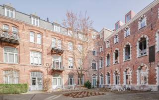 In het prachtige renovatieproject Colleghof in de Oude Houtlei in Gent bevindt zich deze karaktervolle herontwikkeling van het voormalige Sint-Amanduscollege. Gelegen in de historische Gentse binnenstad, op wandelafstand van de Sint-Michielskerk, de Korenmarkt en de Veldstraat, combineert deze locatie rust met het bruisende stadsleven.<br /><br />U betreedt het appartement via de inkomhal die toegang geeft tot de lichtrijke leefruimte met open keuken. De indrukwekkende hoge plafonds zorgen meteen voor een ruim en uniek gevoel. Vanuit de leefruimte heeft u toegang tot het inpandige terras met zicht op een mooie, rustige binnentuin.<br /><br />De mezzanine biedt extra ruimte en is ideaal als bureau, werkplek of leeshoek. Het appartement beschikt over twee volwaardige slaapkamers, elk met een eigen badkamer, wat zorgt voor extra comfort en privacy.<br /><br />Verder is er een ruime berging met aansluiting voor wasmachine en droogkast en 2 toiletten<br /><br />Troeven:<br /><br />- Topligging in het historisch centrum van Gent<br />- Karaktervolle renovatie in voormalig college<br />- Hoge plafonds en mezzanine<br />- Inpandig terras met zicht op binnentuin<br />- 2 slaapkamers met eigen badkamer<br />- Ruime berging<br /><br />Optioneel: mogelijkheid tot aankoop van 2 ondergrondse staanplaatsen (50.000 euro per staanplaats).