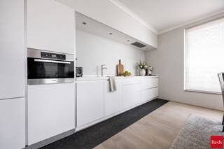 <strong>Stijlvol wonen aan het water – Kattendijkdok Westkaai 51 bus 3.4, Antwerpen</strong><br /><br />Welkom in dit prachtige appartement op een absolute toplocatie aan het bruisende Eilandje. Hier geniet u dagelijks van een uniek uitzicht op het Kattendijkdok, gecombineerd met de levendigheid van de stad, een uitstekende bereikbaarheid en een uitzonderlijke woonkwaliteit.<br /><br />Het gebouw werd ontworpen door de gerenommeerde Zwitserse architect Roger Diener en staat bekend om zijn tijdloze, minimalistische architectuur en hoogwaardige afwerking.<br /><br />Met een bewoonbare oppervlakte van ca. 103 m² biedt dit appartement een perfecte balans tussen ruimte, comfort en elegantie. De ruime leefruimte wordt gekenmerkt door grote raampartijen die zorgen voor een overvloed aan natuurlijk licht en een aangename connectie met de omgeving. Vanuit de leefruimte heeft u toegang tot het westgericht terras, waar u in alle rust kunt genieten van de middag- en avondzon. Het uitzicht combineert het beste van twee werelden: een zicht op het water enerzijds en een levendig stadszicht anderzijds.<br /><br />De open designkeuken is afgewerkt met kwaliteitsmaterialen en uitgerust met hoogwaardige Miele-toestellen, wat garant staat voor optimaal kookcomfort. De leefruimte werd bovendien voorzien van externe zonnewering, waardoor het appartement ook tijdens warme zomerdagen aangenaam blijft.<br /><br />Doorheen vrijwel het volledige appartement werd een kwalitatieve parketvloer doorgetrokken, wat zorgt voor een warme, stijlvolle en uniforme uitstraling. Enkel in de badkamer en het toilet werd gekozen voor een onderhoudsvriendelijke tegelvloer.<br /><br />Het appartement beschikt over twee ruime slaapkamers, een comfortabele badkamer, twee afzonderlijke toiletten en een praktische berging. Dankzij de doordachte indeling is dit appartement uitermate geschikt als gezinswoning, stijlvolle stadswoning of kwalitatieve investering.<br /><br /><strong>Extra troeven:</strong><br /><br />Westgericht terras<br />Zicht op zowel het water als de stad<br />Volledig doorgetrokken parketvloer<br />Hoogwaardige Miele-keukentoestellen<br />Externe zonnewering aan de leefruimte<br />Twee ruime slaapkamers<br />Topligging op het Eilandje<br />Nabij restaurants, musea, winkels en openbaar vervoer<br />Kelderberging en gemeenschappelijke fietsenberging<br />Energiezuinig en voorzien van hedendaags wooncomfort<br /><br />Ondergrondse parkeerplaats optitioneel aan te kopen voor €40.000.<br /><br />Een uitzonderlijk appartement op een van de meest gegeerde locaties van Antwerpen, waar architectuur, comfort en ligging naadloos samenkomen.<br /><br />Voor meer informatie of een bezoek ter plaatse kan u contact opnemen met Xander via 0497 18 10 84 of xander@reds.be.