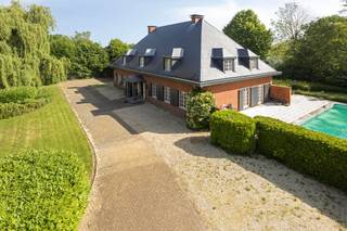 <p><strong><em>Villa élégante (584 m²) avec 7 chambres, 2 dressings, salle de bain et salle de douche, bureau + espace de travail, double garage, grenier, cave, grande terrasse avec piscine et magnifique jardin de parc avec court de tennis sur une parcelle de 51a 14ca offrant une grande intimité à Herent.</em></strong><br /><strong><em>Possibilités certaines pour une maison kangourou, bureau, cabinet ou profession libérale.</em></strong></p><p>Située dans un endroit calme et très privé, cette villa raffinée dévoile une habitation spacieuse où chaleur et générosité se mêlent naturellement. Avec ses vastes espaces de vie, ses sept chambres, ses deux dressings, ses espaces de travail et son jardin de parc étendu, cette maison constitue un lieu de vie particulièrement accueillant pour ceux qui recherchent confort, élégance et polyvalence.</p><p>Le large hall d’entrée avec vestiaire et toilette invités mène à un séjour lumineux en forme de L, agrémenté de pierre naturelle, d’un foyer au gaz intégré et de mobilier sur mesure apportant calme et raffinement. Les grandes baies vitrées offrent une vue superbe sur le jardin et un accès direct à la vaste terrasse.<br />La cuisine attenante, aménagée avec goût, présente des plans de travail en pierre naturelle, un parquet massif et une charmante baie vitrée avec coin repas donnant sur la verdure.</p><p>Au rez-de-chaussée se trouve également un bureau spacieux de 31 m², complété par un espace de travail de 41 m² équipé de l’air conditionné. Cette aile est idéale pour une pratique, une profession libérale ou un bureau à domicile.<br />Le double garage et l’allée permettent un stationnement confortable.</p><p>Le premier étage dévoile un hall de nuit central avec toilette séparée, une salle de bain rénovée en pierre naturelle avec baignoire et douche, une salle de douche distincte et pas moins de sept chambres, dont certaines avec placards intégrés et lavabo. La chambre principale dispose de deux dressings séparés, renforçant la sensation d’espace et de luxe.</p><p>Au-dessus, un grand grenier de 88 m² offre des possibilités d’extension pour ceux qui souhaitent encore davantage d’espace.<br />La cave (30 m²) comprend notamment une installation de chauffage récemment remplacée, un adoucisseur d’eau et une cave à vin réfrigérée. Un vide sanitaire est également présent.</p><p>À l’extérieur, la terrasse de 82 m² constitue un lieu de détente privilégié, directement relié à la piscine chauffée orientée plein sud.<br />Le jardin de parc paysager respire la tranquillité et l’intimité, et comprend un court de tennis entièrement aménagé, un atout supplémentaire rare sur un domaine de cette qualité.</p><p>Atouts supplémentaires :<br />EPC : 244 kWh/m²/an (label C) – Toiture en ardoises naturelles rénovée en 2015 – Installation de chauffage récemment remplacée.<br />Puits d’eau souterraine.<br />Adoucisseur d’eau.<br />Système d’alarme – vidéophone.</p><p>L’emplacement combine calme et accessibilité : le centre d’Herent et toutes ses commodités sont accessibles à vélo, tout comme Louvain. L’accès à l’E314 se trouve à dix minutes, et Bruxelles est facilement joignable. La propriété est accessible via une allée privée, renforçant encore la discrétion du lieu.<br />Un cadre unique pour vivre et travailler en toute sérénité.</p>