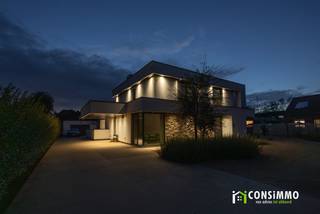Deze <strong>exclusieve, moderne villa</strong> combineert een verfijnde architectuur met een bijzonder hoog niveau van wooncomfort en energiezuinigheid. Met een vloeroppervlakte van maar liefst <strong>248 m²</strong>, een royaal perceel van <strong>18a 11ca</strong> en een uitzonderlijk <strong>EPC-label A met een energiescore van slechts 5 kWh/m² per jaar</strong>, werd hier duidelijk gekozen voor ruimte, kwaliteit en duurzaamheid. De hoogwaardige afwerking, maatwerkkasten en doordachte indeling trekken die lijn doorheen de volledige woning.<br /><br /><strong>Indeling</strong><br />De royale inkomhal met <strong>indrukwekkende vide</strong> zet meteen de toon. Ingebouwde vestiairekasten zorgen voor een strakke afwerking en via een stijlvolle stalen deur bereikt u de lichtrijke leefruimte. In de living treffen we ook een gezellige doorkijkhaard, met zicht op de keuken. Verder treffen we een bijkomend hoekje dat zich uitstekend leent als bureau, lees- of speelhoek. Op het gelijkvloers bevindt zich tevens een afzonderlijk bureau en gastentoilet.<br />Aansluitend vinden we de eetkamer en de hoogwaardig afgewerkte keuken, uitgevoerd in kwalitatieve materialen en voorzien van alle moderne inbouwtoestellen. De aangrenzende berging met maatwerkkasten biedt volop praktische opslagruimte.<br /><br />Op de verdieping bevinden zich <strong>drie ruime slaapkamers</strong>. De masterbedroom beschikt over een eigen dressing, terwijl de twee overige slaapkamers uitgerust zijn met inbouwkasten. Iedere slaapkamer beschikt bovendien over een eigen <strong>airco-warmtepomp voor zowel koeling als verwarming</strong>.<br />Ook de badkamer sluit perfect aan bij het luxueuze karakter van de woning en werd hoogwaardig afgewerkt met een ruime inloopdouche, ligbad, dubbele lavabo en toilet. Een afzonderlijke linnenkamer met maatwerkkasten en aansluitingen voor wasmachine en droogkast vervolledigt deze verdieping.<br /><br />De functionele kelder biedt nog heel wat bijkomende mogelijkheden en kan worden ingericht als <strong>fitnessruimte, hobbykamer, speelruimte of extra opslagruimte</strong>. Dankzij de afzonderlijke toegang langs buiten is deze ruimte bovendien bijzonder praktisch, wat het ook geschikt maakt om het in te richten als <strong>kantoor </strong>of <strong>praktijkruimte</strong>.<br /><br />Vanuit zowel de leefruimte als de keuken bereikt u het <strong>overdekte terras en de bijzonder ruime tuin</strong>. Achteraan bevindt zich een garage met bijkomende opslagruimte. Aan de voorzijde biedt de royale oprit met een architecturale <strong>zwevende carport</strong> plaats aan meerdere wagens en bezoekers. Het perceel wordt afgesloten met een hoogwaardig afgewerkte, automatisch bedienbare poort.<br /><br /><strong>Technische informatie</strong><br />Ook energetisch bevindt deze villa zich op een uitzonderlijk niveau. Met een <strong>EPC-label A en een energiescore van amper 5 kWh/m² per jaar</strong> benadert de woning een bijna-energieneutraal niveau. De woning is doorgedreven geïsoleerd, bovenop de geldende vereisten, en wordt verwarmd via vloerverwarming op aardgas. Daarnaast zijn er <strong>24 zonnepanelen met een totaal piekvermogen van circa 8 kWp</strong>, gecombineerd met een thuisbatterij. Een ventilatiesysteem type D zorgt voor een continue en gecontroleerde luchtverversing. De aluminium ramen met superisolerende beglazing dragen verder bij aan het uitstekende wooncomfort.<br /><br /><strong>Buurtinformatie</strong><br />De villa bevindt zich in een <strong>residentiële omgeving van Genk waar rust, ruimte en dagelijks comfort mooi samenkomen</strong>. Op wandelafstand vindt u onder meer openbaar vervoer en een kleuter- en basisschool, terwijl supermarkten, bakkers, apotheken, medische voorzieningen en andere dagelijkse faciliteiten vlot bereikbaar zijn. Ook het <strong>Ziekenhuis Oost-Limburg</strong> bevindt zich in de nabije omgeving en <strong>Genk-Centrum ligt op amper vijf minuten rijden</strong>.<br />Wie graag in het groen vertoeft, vindt met onder meer <strong>Kattevennen</strong> en de omliggende natuur tal van mogelijkheden om te wandelen, sporten en ontspannen. De ruime, groene omgeving is bovendien bijzonder aangenaam voor gezinnen en dierenliefhebbers. Tegelijk wordt er verder geïnvesteerd in de omgeving, wat bijdraagt aan de verdere kwalitatieve ontwikkeling van de buurt.<br /><br />Een villa voor wie geen keuze wil maken tussen <strong>architectuur, ruimte, luxe en uitzonderlijke energiezuinigheid</strong>.<br />Bent u op zoek naar een <strong>exclusieve villa met een hoogwaardige afwerking, een riante tuin en uitzonderlijke energetische prestaties</strong>? Contacteer ons via <strong>089 69 30 01</strong> of <strong>info@consimmo.be</strong> voor meer informatie of een bezoek ter plaatse. <strong>Bekijk ook de virtuele tour op onze website </strong><strong>www.consimmo.be</strong><strong>.</strong>
