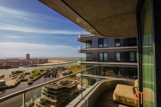 <strong>Uniek wonen op de 21ste verdieping aan de Oosteroever</strong><br /><br />Op zoek naar een <strong>exclusief appartement te koop in Oostende met zeezicht</strong>?<br />Dit prachtig afgewerkte appartement op de <strong>21ste verdieping in de begeerde wijk Oosteroever</strong> biedt een uitzonderlijke woonbeleving met sublieme vergezichten over de <strong>zee, duinen, haven en de skyline van Oostende</strong>.<br /><br />Dit hedendaagse appartement, gebouwd in <strong>2021</strong>, combineert een hoogwaardige afwerking met hedendaags comfort en een indrukwekkende ligging. Dankzij de grote hoogte geniet u vanuit de leefruimtes en de masterbedroom van een uniek en voortdurend veranderend panorama.<br /><br /><strong>Ruime woonkamer met terras en adembenemend uitzicht</strong><br />Via de inkomhal komt u in de stijlvolle en aangename leefruimte.<br />De <strong>ruime woonkamer met sierhaard</strong> vormt het hart van het appartement en geniet dankzij de ligging op de 21ste verdieping van bijzonder veel licht en prachtige vergezichten.<br />Aansluitend bevindt zich het <strong>aangename terras</strong>, de ideale plek om te genieten van een ochtendkoffie, een aperitief bij zonsondergang of simpelweg van het weidse uitzicht over <strong>zee, duinen, haven en stad</strong>.<br />De volledige leefruimte is afgewerkt met <strong>parket</strong>, wat zorgt voor een warme en elegante uitstraling.<br /><br /><strong>Hedendaagse open keuken, volledig ingericht</strong><br />De moderne, open keuken sluit naadloos aan bij de woonkamer en vormt een stijlvol en functioneel geheel.<br />De keuken is <strong>volledig ingericht</strong> en biedt alles wat nodig is voor comfortabel dagelijks wonen en gezellig tafelen.<br />De open indeling versterkt het gevoel van ruimte en zorgt voor een aangename verbinding tussen keuken, eet- en leefruimte.<br /><br /><strong>Drie slaapkamers, waaronder een masterbedroom met subliem zeezicht</strong><br />Het appartement beschikt over <strong>3 volwaardige slaapkamers</strong>.<br />De <strong>masterbedroom</strong> is een echte troef en biedt eveneens een prachtig <strong>zicht op zee</strong>. Deze slaapkamer beschikt bovendien over een <strong>eigen badkamer met ligbad, dubbele lavabo en toilet</strong>, wat zorgt voor extra privacy en comfort.<br />De twee overige slaapkamers zijn ideaal als logeerkamers, kinderkamers, dressing of thuiskantoor. Zij delen een tweede badkamer, uitgerust met een <strong>douche en lavabo</strong>.<br />Daarnaast beschikt het appartement over een <strong>afzonderlijk gastentoilet</strong> en een praktische <strong>bergruimte</strong>.<br /><br /><strong>Hoogwaardige afwerking en hedendaags wooncomfort</strong><br />Het appartement werd gebouwd in <strong>2021</strong> en is bijzonder mooi afgewerkt. De aanwezigheid van <strong>parket doorheen het appartement</strong> zorgt voor een luxueuze en uniforme uitstraling.<br />Voor het verwarmingscomfort is er <strong>vloerverwarming</strong>, aangesloten op het <strong>warmtenet</strong>. Met een <strong>EPC-label A</strong> combineert deze woning hedendaags comfort bovendien met een uitstekende energieprestatie.<br /><br /><strong>Garage mogelijk in de directe omgeving</strong><br />Er bestaat de <strong>mogelijkheid tot aankoop van een garage in de directe omgeving</strong> van het appartement. Een interessante extra troef voor wie comfortabel en veilig wil parkeren in Oosteroever.<br /><br /><strong>Exclusief appartement te koop in Oostende Oosteroever</strong><br />Dit ruime en luxueus afgewerkte <strong>3-slaapkamerappartement in Oostende – Oosteroever</strong> is een unieke kans voor wie op zoek is naar een hoogwaardige woonst op grote hoogte, met <strong>panoramisch zeezicht en zicht over de haven, duinen en stad</strong>.<br /><br />De combinatie van de <strong>21ste verdieping, het uitzonderlijke uitzicht, het ruime terras, 3 slaapkamers, 2 badkamers, open keuken, parketafwerking, vloerverwarming, warmtenet en EPC A</strong> maakt dit appartement bijzonder aantrekkelijk als permanente woning, tweede verblijf of kwalitatieve investering aan de Belgische kust.<br /><br /><strong>Kenmerken in het kort</strong><br /><span>Aangenaam terras met prachtig uitzicht</span><br /><span>Prachtige parketafwerking doorheen het appartement</span><br /><span>Bouwjaar 2021</span><br /><span>EPC : label A</span><br /><span>Vloerverwarming - aangesloten op het warmtenet</span><br /><span>KI: € 1.102</span><br /><span>Mogelijkheid tot aankoop van garage in de directe omgeving</span><br /><br /><strong>Een exclusieve woonbeleving op hoogte, met de zee als dagelijkse achtergrond.</strong><br />