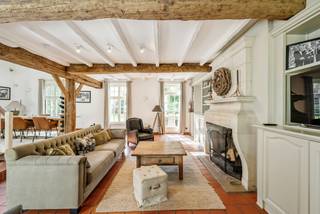 Op een discreet perceel treffen we deze karaktervolle villa in landelijke architectuur. De woning is omgeven door een volwassen tuin met imposante bomen en geniet hierdoor van een aangename privacy.<br /><br />Binnen valt meteen het warme karakter van de woning op. De royale leefruimte wordt gekenmerkt door zichtbare houten balken, een terracottavloer, een natuurstenen open haard en talrijke raampartijen die voor veel natuurlijk licht en een mooie verbinding met de tuin zorgen. De hedendaagse leefkeuken vormt samen met de afzonderlijke ontbijthoek een aangename dagelijkse leefplek. Met 3 a 4 slaapkamers, twee badkamers, een ruim bureau, een inpandige garage en een volwaardige master suite biedt deze woning bovendien een bijzonder comfortabele gezinsindeling.<br /><br />Indeling gelijkvloers:<br />De inkomhal geeft toegang tot de verschillende vertrekken op het gelijkvloers. Een afzonderlijk en lichtrijk bureau, voorzien van brede raampartijen met zicht op het groen, biedt een aangename thuiswerkplek en kan tevens polyvalent worden ingericht.<br /><br />Centraal in de woning bevindt zich de ruime leefkamer met zit- en eetgedeelte. De houten balkenstructuur, terracottavloer en natuurstenen open haard zorgen hier voor een warme en karaktervolle uitstraling. Grote ramen en tuindeuren versterken het contact met de omliggende tuin. De open trap en vide geven het geheel bovendien een aangenaam gevoel van ruimte.<br /><br />De leefkeuken werd hedendaags ingericht met een royaal centraal kookeiland, veel kastruimte en kwalitatieve toestellen. Aansluitend bevindt zich een afzonderlijke ontbijthoek met veel natuurlijke lichtinval.<br /><br />Verder beschikt het gelijkvloers over een inpandige garage die eveneens plaats biedt aan de wasvoorzieningen en bijkomende bergruimte.<br /><br />Eerste verdieping:<br />De eerste verdieping omvat een volwaardig slaapgedeelte met in totaal 3 slaapkamers en een dressing die ook als 4e slaapkamer kan dienen.<br /><br />Een ruime hoofdslaapkamer, met hiernaast een dressing met maatkasten en hiernaast een badkamer. Deze badkamer is uitgerust met een dubbele wastafel, ligbad en afzonderlijke douche.<br /><br />Daarnaast bevinden zich op deze verdieping nog 2 bijkomende slaapkamers, geschikt als kinder-, logeer- of hobbykamers en een ruime bureauhoek op de overloop. Zij beschikken over een 2e badkamer met ligbad, wastafel en toilet.<br /><br />Kelder:<br />Onder een gedeelte van de leefruimte bevindt zich een praktische / wijn- kelder, bereikbaar via een luik in de vloer, eveneens geschikt als bijkomende voorraad- of bergruimte.<br /><br />Tuin:<br />De woning is mooi ingeplant op een ruim en volwassen aangelegd perceel. Grote gazonpartijen, volgroeide bomen, hagen en groenmassieven zorgen voor een bijzonder aangenaam kader en een hoge mate van privacy. De kasseiverharding en landelijke architectuur sluiten harmonieus aan bij het groene karakter van de eigendom.<br /><br />Bijzonderheden:<br />- Perceel van ca. 3.743 m² volgens opmetingsplan<br />- Nuttige oppervlakte volgens kadaster ca. 326 m²<br />- 3 à 4 slpks<br />- 2 badkamers<br />- Ruim afzonderlijk bureau<br />- Asbestveilig<br />- P-score A – G-score A