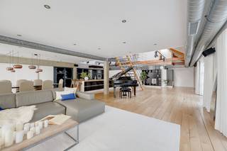<p>In een historisch gebouw met uitgesproken industrieel karakter aan de Van de Wervestraat, op een boogscheut van Park Spoor Noord en het Antwerpse Eilandje, bevindt zich deze uitzonderlijk ruime en karaktervolle loft. Gelegen in het rustige binnengebied combineert dit unieke eigendom authentieke elementen, royale volumes en een bijzonder flexibele indeling.<br />Via de inkomhal met vestiaire en gastentoilet betreden we de indrukwekkende leefruimte, volledig afgewerkt met parket en gekenmerkt door een aangename plafondhoogte. De ruime industriële keuken is volledig uitgerust met onder meer een stoomoven, hete luchtoven, inductiekookplaat en één gaskookpit, koelkast, diepvries en vaatwasser. Vanuit de leefruimte is er toegang tot twee aangename terrassen, aan de voor- en zijkant van de loft, beide met een gunstige zuidoriëntatie.<br /><br />Een industriële trap leidt naar de mezzanine, waar zich twee ruime slaapkamers bevinden. Aansluitend aan de leefruimte vinden we een praktische was- en technische berging en een royale, centraal gelegen badkamer met groot ligbad, inloopdouche, dubbele lavabo en toilet. De aansluitende inloopdressing met ingemaakte kasten zorgt voor extra comfort en opbergruimte. Vanuit de inkomhal is bovendien een bijkomende slaapkamer bereikbaar, voorzien van dubbele ramen die rechtstreeks toegang geven tot één van de terrassen.<br /><br />Een bijzondere extra troef is het afzonderlijke gedeelte dat via een wenteltrap bereikbaar is. Dit gedeelte beschikt over een eigen leefruimte, (rudimentair) keukenblok, douchekamer met toilet en een ruime kamer op de bovenverdieping kan dit gedeelte perfect functioneren als aparte studio, gastenverblijf, werkruimte of bijkomende slaapvertrekken. Hierdoor leent de loft zich eveneens uitstekend tot co-housing of een combinatie van wonen en werken.<br /><br />Tot slot vormt de ondergrondse autostaanplaats een belangrijke meerwaarde en zorgt deze voor extra comfort op deze centrale Antwerpse locatie. Deze staanplaats is bij aan te kopen.<br />Een unieke loft voor wie op zoek is naar ruimte, industrieel karakter, buitenruimte en tal van indelingsmogelijkheden op een uitstekende locatie nabij Park Spoor Noord en het Eilandje.<br /><br />Interesse in deze unieke loft?<br />Contacteer ons via 03 337 50 70 of info@vbvastgoed.be voor meer info of een bezoek ter plaatse.</p>