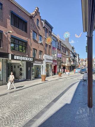 In de levendige Stapelstraat in Sint-Truiden bevindt zich dit veelzijdige handelspand met bovenliggende woonst. De centrale ligging tussen winkels, horeca en andere diensten zorgt voor een goede commerciële zichtbaarheid en passage. Een interessante locatie voor wie een eigen zaak wil uitbouwen en wonen en werken wil combineren.<br /><br />Het pand beschikt over een totale oppervlakte van circa 148 m² volgens het EPC. Op het gelijkvloers bevindt zich een handelsruimte van circa 62 m², die vroeger dienstdeed als bakkerij. De ruimte is momenteel niet meer ingericht en biedt een neutrale basis voor een nieuwe commerciële invulling, afgestemd op uw activiteiten en wensen. De aansluitende achterruimte is praktisch voor opslag of ter ondersteuning van de handelsactiviteit.<br /><br />Het woongedeelte strekt zich uit over de bovenliggende verdiepingen en omvat een aangename leefruimte, een ingerichte keuken met toegang tot het terras, een badkamer en twee tot drie slaapkamers. Daarnaast is er een ruime zolder, die extra opslagruimte biedt of verder ingericht kan worden, mits de nodige vergunningen.<br /><br />Ook de bereikbaarheid vormt een troef. Parkeermogelijkheden, openbaar vervoer en het station van Sint-Truiden bevinden zich in de nabije omgeving, terwijl de centrale ligging zorgt voor dagelijkse voorzieningen binnen handbereik.<br /><br />De combinatie van handelsruimte en woonst maakt deze eigendom aantrekkelijk voor zelfstandigen die hun zaak en woning op één adres willen onderbrengen. Ook voor investeerders die een veelzijdig pand in het centrum van Sint-Truiden zoeken, biedt deze eigendom mogelijkheden.<br /><br />Benieuwd wat dit pand voor uw plannen kan betekenen? Contacteer Meyers Vastgoed voor meer informatie of een bezichtiging ter plaatse.