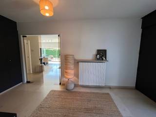 Bij het binnenkomen in de woning is er onmiddellijk een inkomhall met ingebouwde vestiaire, een apart gastentoilet en toegang naar de ruime garage (met automatische poort) Vanuit de inkom is er eveneens toegang tot de ruime en lichtrijke woonkamer, er is een aparte ingerichte keuken met plaats voor een tafel, alles uitgevend op een zonnige terras (met zonnestore) en de private aangelegde tuin, op het gelijkvloers zijn er 3 slaapkamers, waarvan 1 met dressing,  een mooie ingerichte badkamer met douche en toilet. aparte berging. Op de  verdieping (enkel toegankelijk via garage) bevindt zich nog een vierde kamer en een zolderruimte. De woning beschikt naast de inpandige garage ook nog over 2 parkeerplaatsen, en een tuinhuis met elektriciteit. Er is regenwater. De villa beschikt over een lopende en goedgekeurde  bouwvergunning om een villa met boven 4 slaapkamers en 4 badkamers te creëren. Momenteel verhuurd aan 2495€/mnd tot 01/12/2026 -  Vrij &amp; beschikbaar vanaf februari 2027.