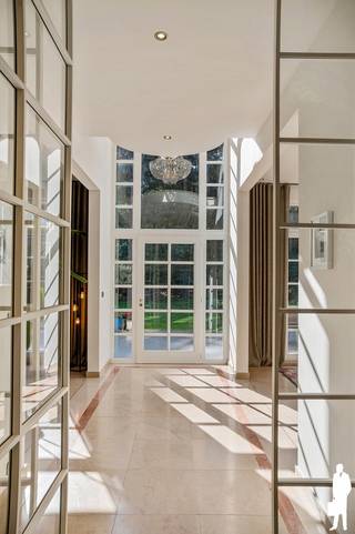 <p><strong>Karaktervolle villa op prachtig bosrijk perceel met 5 slaapkamers, 3 badkamers en uitzonderlijk veel ruimte</strong><span></span></p>
<p>Deze <strong>ruime en karaktervolle villa</strong> is bijzonder mooi ingeplant in een <strong>volledig groene en bosrijke omgeving</strong> en combineert een tijdloze architectuur met een uitzonderlijk woonvolume. De verschillende leefvertrekken, <strong>5 slaapkamers</strong>, <strong>3 badkamers</strong>, royale zolderverdieping en prachtige tuin maken dit tot een bijzonder veelzijdige gezinswoning.</p>
<p><strong>Gelijkvloerse verdieping</strong><br />- ruime <strong>inkomhal</strong> met gastentoilet en vestiaire<br />- verschillende <strong>leefvertrekken</strong> met mooie verbinding tussen de ruimtes en veel natuurlijk licht<br />- gezellige <strong>woonkamer</strong> met zicht en toegang tot de tuin<br />- afzonderlijke <strong>eetkamer</strong><br />- ingerichte <strong>keuken</strong> met aansluitende praktische ruimtes<br />- volwaardig <strong>bureel</strong>, ideaal als thuiskantoor of praktijkruimte<br />- bijkomende <strong>TV-/familiekamer</strong><br />- praktische <strong>bijkeuken/berging</strong><br />- <strong>dubbele inpandige garage</strong><br />- <strong>kelderruimte</strong></p>
<p><strong>Eerste verdieping</strong><br />- centrale <strong>nachthal</strong><br />- royale <strong>masterbedroom</strong> met aansluitende <strong>dressing</strong><br />- bijzonder ruime en recent ingerichte <strong>badkamer ensuite</strong> met ligbad, inloopdouche en dubbele wastafel<br />- <strong>2 ruime slaapkamers</strong><br />- tweede <strong>badkamer</strong><br />- afzonderlijk gedeelte met <strong>5de slaapkamer en eigen badkamer</strong>, ideaal als gastenverblijf of voor een au-pair<br />- toegang tot de hoger gelegen verdieping</p>
<p><strong>Tweede verdieping</strong><br />- <strong>4de slaapkamer</strong><br />- uitzonderlijk ruime, open <strong>zolderverdieping</strong> met prachtige dakstructuur en veel daglicht<br />- momenteel ingericht als <strong>fitness-, hobby- en ontspanningsruimte</strong><br />- tal van mogelijkheden als extra leefruimte, speelkamer, atelier of combinatie van verschillende functies</p>
<p><strong>Tuin en buitenruimte</strong><br />- prachtig <strong>bosrijk perceel</strong> met uitzonderlijk veel privacy<br />- woning mooi en discreet ingeplant tussen het groen<br />- royale <strong>terrassen</strong> aansluitend op de leefruimtes<br />- sfeervolle <strong>vijver</strong> met houten vlonder<br />- verschillende wandelpaadjes en charmante zithoekjes doorheen de tuin<br />- ruime <strong>oprit</strong> met veel parkeermogelijkheden<br />- bijzonder rustige en groene woonbeleving</p>
<p><strong>Bijzonderheden</strong><br />- <strong>5 slaapkamers en 3 badkamers</strong><br />- <strong>uitzonderlijk ruim woonvolume</strong><br />- combinatie van <strong>wonen, werken en ontspannen</strong> onder één dak<br />- prachtige <strong>master suite met dressing en vernieuwde badkamer</strong><br />- indrukwekkende <strong>multifunctionele zolderverdieping</strong><br />- veel natuurlijke lichtinval en mooie zichtassen naar het groen<br />- <strong>dubbele inpandige garage</strong><br />- <strong>zonnepanelen</strong><br />- uitzonderlijke <strong>privacy en bosbeleving</strong></p>
<p><strong>Ligging</strong></p>
<p>Gelegen in de bijzonder gegeerde en groene omgeving van <strong>Kapellenbos</strong>. De woning geniet van een uitzonderlijk rustige ligging midden in het groen en biedt tegelijk een vlotte verbinding met het centrum van Kapellen, Heide-Kalmthout en de omliggende gemeenten.</p>
<p>Een <strong>bijzonder ruime en karaktervolle villa </strong>waar privacy, wooncomfort en veelzijdigheid centraal staan.</p>