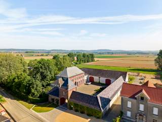 <p><strong>Exclusieve vierkantshoeve te koop in Arc-Wattripont – luxe, rust en authenticiteit </strong></p>
<p>Op een domein van drie hectare ligt deze uitzonderlijke vierkantshoeve, volledig gerenoveerd met behoud van haar authentieke charme. De eigendom biedt privacy, ruimte en verfijning in een idyllische, groene omgeving.</p>
<p>De hoofdwoning verwelkomt u met een statige inkomhal, bureauruimte, eetplaats, twee gezellige salons met haardvuur en een lichtrijke orangerie met uitzicht op de tuin. De landelijke keuken met Aga-fornuis sluit aan op een bijkeuken, wasplaats, berging, stookruimte en wijnkelder. Op de verdieping bevinden zich drie ruime slaapkamers, een dressing, twee badkamers, een fitnessruimte en een zolder met uitbreidingspotentieel.</p>
<p>Het buitengedeelte ademt luxe en rust: een zwembad van 12,50 bij 5.00 meter met een vorig jaar volledig vernieuwd Coverseal afdekking, poolhouse (sauna, douche, zithoek met haard), een overdekt terras met open zicht, stenen bakoven, gerenoveerde serre, vijver en een prachtige tuin met oude bomen. Daarnaast vindt u een conciergerie (vakantiehuis met 3 slaapkamers, keuken, salon, badkamer en wc), een grote schuur met indrukwekkend gebinte (perfect als feestzaal), paardenstallen (10 boxen), piste en weides.</p>
<p>Zonnepanelen zorgen voor energie-efficiëntie. Er is bovendien mogelijkheid tot aankoop van ca. zes hectare weides en grond.</p>
<p>Deze luxe hoeve in Arc-Wattripont is een unieke kans voor wie houdt van exclusief wonen in harmonie met de natuur. Een perfect evenwicht tussen elegantie, comfort en rust — klaar om in te trekken.<br /><br />Voor inlichtingen en/of bezoek, bel Stéphanie Eeckhout <strong>0472/13.28.79</strong></p>
