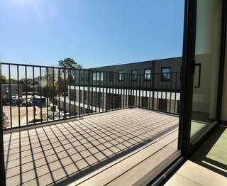 Welkom bij het Edward Poppe Woonpark, een uniek nieuwbouwproject in Sint-Laureins. Dit woonproject, gelegen op de terreinen van het voormalige Edward Poppe Instituut aan de Rommelsweg, biedt een harmonieuze combinatie van moderne architectuur en historische charme. Het project is ontworpen met oog voor detail en duurzaamheid.
Het Edward Poppe Instituut, gebouwd in 1962, diende jarenlang als een vertrouwde brug tussen de basisschool in Sint-Laureins en de grotere secundaire scholen in Eeklo, Maldegem en Gent. Het gebouw, bekend om zijn modernistische stijl en familiaire sfeer, is een herkenningspunt in de regio en biedt een prachtige basis voor dit nieuwe woonproject.
Het Edward Poppe Woonpark streeft naar een energie-neutraal karakter. Geen gebruik van fossiele brandstoffen, maar wel van warmtepompen en zonnepanelen, duurzame materialen en hergebruik en renovatie van bestaande structuren. De circulatie van auto's is slim ontworpen aan de buitengrenzen van het perceel, waardoor de kern van het project een groene oase blijft.
De indeling is als volgt: een grote inkomhal met gastentoilet, een lichtrijke leefruimte met een open keuken voorzien van alle hedendaagse comfort met voldoende opbergruimte, een terras met een prachtig uitzicht op de gemeenschappelijke tuin, 2 slaapkamers, een badkamer, een grote berging/wasplaats, een privatieve fietsenberging/berging en een privatieve autostaanplaats.
Het appartement is volledig geschilderd en instap klaar.
Alle leefruimtes kijken uit op een centraal groen park, dat dienst doet als ontmoetingsplaats voor jong en oud. Het park, met zijn glooiende reliëf, draagt bij aan een natuurlijke speelomgeving en fungeert tevens als wadi.
Wonen in Sint-Laureins biedt tal van voordelen. De gemeente staat bekend om haar uitstekende leefkwaliteit, met een sterke focus op natuur, rust en veiligheid. Daarnaast zijn er uitgebreide voorzieningen voor sport, cultuur en recreatie. De nabijheid van stedelijke centra zoals Eeklo, Maldegem en Gent zorgt ervoor dat stedelijke voorzieningen altijd binnen handbereik zijn.
Ontdek de perfecte balans tussen historisch erfgoed en modern wooncomfort in het Edward Poppe Woonpark. Wenst u een bezoek aan het gelijkvloers appartement? Maak uw afspraak via www.vastgoedunicum.be of mail naar verhuur@vastgoedunicum.be.