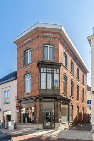 Het gebouw bestaat momenteel uit een handelspand op het gelijkvloers en 2 appartementen op de bovengelegen verdiepingen.

De handelsruimte (66 m²) op het gelijkvloers doet dienst als kapperszaak. Dankzij de praktische indeling leent deze ruimte zich voor diverse commerciële activiteiten, doch hoeft deze ruimte geen handelszaak te blijven.

Op de 1ste verdieping vinden we een studio (66 m²). De studio straalt charme uit, dankzij de hoge plafonds en de authentieke, houten vloer. De witte keuken beschikt over een keramische kookplaat en wasbak. De badkamer is voorzien van een douche in bad, toilet en lavabo.

Op de 2de verdieping bevindt zich een duplex appartement. We komen binnen in de ruime woonkamer met open keuken (57 m²). De praktische keuken is uitgerust met een inductiekookplaat, combi-oven, steamer, afwasmachine en wasbak. Achter de keuken vinden we de badkamer, die voorzien is van een bad, toilet en dubbele lavabo. De drie ruime kamers (30, 17 en 16 m²) bevinden zich op de bovengelegen verdieping. Deze beschikken allen over ingemaakte kasten.

Daarnaast is er een ruime kelder (41 m²), waar de aansluitingen voor wasmachine en droogkast voorzien zijn en waar zich tevens een extra douche bevindt.

Dit pand wordt verwarmd op stookolie, maar een overschakeling naar aardgas is mogelijk. De ramen zijn van dubbel glas (hout- en pvc-profielen). Het pand heeft EPC-attesten met labels C en D, waardoor er geen renovatieverplichting geldt. De elektriciteit is niet conform het AREI.