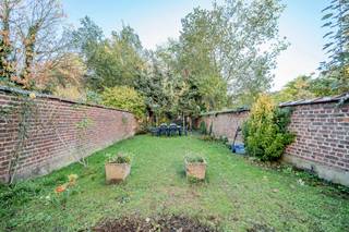 Gelegen in een rustige en residentiële wijk biedt dit gelijkvloers appartement met een oppervlakte van ongeveer 89 m² een aangename en comfortabele woonomgeving. Het bestaat uit een inkomhal, een ruime en lichte woon- en eetkamer, evenals een volledig uitgeruste keuken. Het appartement beschikt momenteel over één slaapkamer, maar een grote ruimte met toegang tot de tuin maakt het mogelijk om eenvoudig een tweede slaapkamer te creëren indien gewenst. Verder is er een douchekamer en een kelder aanwezig. Buiten vindt u een groot terras en een privétuin, ideaal om van zonnige dagen te genieten. Het pand is voorzien van een veiligheidsdeur, dubbele beglazing en nieuwe rolluiken aan alle ramen. Gelegen in een klein gebouw met lage lasten combineert dit appartement comfort, rust en nabijheid van winkels, openbaar vervoer en andere voorzieningen. Zeker een bezoek waard.