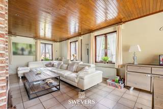 Voor meer info en foto’s, surf naar www.swevers.be – Op een ruim perceel van 980 m² in Heusden-Zolder ligt deze vrijstaande woning met een bewoonbare oppervlakte van circa 190 m². De woning werd gebouwd in 1992 en biedt dankzij haar solide structuur en ruime indeling een uitstekende basis voor wie op zoek is naar een gezinswoning die volledig naar eigen smaak kan worden opgefrist. Via de inkomhal met gastentoilet bereikt u de lichtrijke woonkamer van 42,25 m², waar voldoende ruimte is voor een gezellige zithoek en eetplaats. De aansluitende keuken van 16,20 m² biedt tal van mogelijkheden voor een eigentijdse inrichting. Daarnaast beschikt het gelijkvloers over een aparte bureauruimte en een ruime inpandige garage van 39,38 m² met plaats voor voertuigen, fietsen en extra opslag. Op de verdieping bevinden zich drie volwaardige slaapkamers. De master bedroom van ongeveer 17 m² beschikt over een aparte dressing. De twee overige slaapkamers zijn elk circa 12,26 m² groot. Verder zijn er een badkamer en een afzonderlijk toilet aanwezig. Een absolute meerwaarde is de uitzonderlijk ruime kelder van 109,45 m², ideaal als opslagruimte, hobbyruimte, werkplaats of fitness. Buiten geniet u van een zonnige, zuidgerichte tuin waar rust, privacy en ruimte centraal staan. De open bebouwing versterkt het gevoel van vrijheid en biedt tal van mogelijkheden voor verdere tuininrichting. De woning is gunstig gelegen met scholen op 800 meter, openbaar vervoer op 750 meter, winkels op 1,9 kilometer, restaurants op 1,5 kilometer en een vlotte verbinding naar de snelweg op 5,8 kilometer. Voor meer informatie, bel 011 255 155. Bron bewoonbare oppervlakte: EPC – verslag.