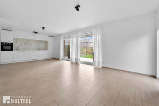 Dit recent en zeer energiezuinig gelijkvloers appartement (Label A) uit 2022 ligt aan de rand van Sint-Niklaas, met een vlotte verbinding naar alle invalswegen. Het maakt deel uit van een kleinschalige residentie en biedt modern comfort in een rustige omgeving. Het appartement omvat een inkomhal met apart toilet, een ruime en lichtrijke leefruimte met open keuken. Aansluitend bevindt zich het overdekt terras met aangrenzende tuin. Verder zijn er twee slaapkamers en een badkamer met douche en lavabomeubel. Dankzij de geothermische warmtepomp en zonnepanelen geniet u van een bijzonder lage energiekost. De provisie voor gemeenschappelijke kosten bedraagt 100 euro per maand en deze geldt als voorschot. In de kelder is een privatieve garagebox aanwezig. Voor het gebouw vindt u een ruime parking en een overdekte fietsenstalling. Een ideaal appartement voor wie comfortabel, duurzaam en rustig wil wonen nabij het centrum van Sint-Niklaas.