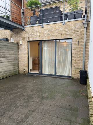 Centraal gelegen gelijkvloers appartement met ruim terras en autostaanplaats onder de gemeenschappelijke carport achteraan te bereiken via uitweg.<br /><br />Het appartement bestaat uit een inkomhal, vooraan een volwaardige slaapkamer met aansluitend de badkamer (lavabo, toilet en bad). Een tweede kamer kan gebruikt worden als berging of extra hobbyruimte. De leefruimte bevat een open en volledig uitgeruste keuken met dubbele spoelbak, kookplaat, oven en frigo.<br /><br />Het ruim terras en de uitweg achteraan zijn extra troeven, het is er ook heel rustig!<br /><br />Voor wie houdt van een centrale ligging en alle modern comfort, is dit appartement de moeite waard!<br /><br />Huurprijs appartement: 695 €/maand<br />Forfait syndic: 55 €/maand<br /><br />Waarborg: 3 maanden huur.<br />EPC label B (163 kwh)<br />CV op aardgas<br />PVC ramen dubbele beglazing<br />Internet + TV distributie<br />Totale oppervlakte: 80 m² + terras <br />Naast de bushalte!