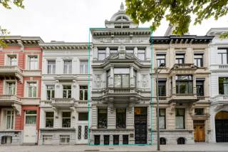 Aan de prestigieuze Amerikalei schittert deze 19e-eeuwse herenwoning, waar historische grandeur en moderne luxe in perfecte harmonie samenkomen. Met een perceel van ca. 333 m² en een woonoppervlakte van ca. 543 m² biedt dit pand vijf verdiepingen vol elegantie en comfort.<br /><br />Achter de statige gevel betreed je een marmeren inkomhal die onmiddellijk de toon zet: elegantie, historie en verfijning. De royale leefruimte baadt in het licht en vloeit harmonieus over in de eetkamer, waar authentieke eer doen aan de rijke geschiedenis van het pand. Aan de achterzijde wacht de leefkeuken met authentieke lichtkoepel, uitgerust met Gaggenau-toestellen en directe toegang tot het terras en de zuidgerichte tuin; een oase van rust midden in de stad.<br /><br />In het souterrain bevindt zich een exclusieve wellness met verwarmd binnenzwembad, sauna en relaxruimte, aangevuld met wijnkelder, wasplaats en een multifunctionele kamer. De verdiepingen erboven huisvesten een master suite met uitzicht op de Leien, slaapkamers met eigen badkamers en dressings, en een elegante bureauruimte met zicht op de tuin. De bovenste verdieping verrast met een royale ontspanningsruimte en panoramisch zicht op het Museum voor Schone Kunsten.<br /><br />Een uitzonderlijk aanbod waar authenticiteit en hedendaags wooncomfort samensmelten. <br />Optioneel is een overdekte autostaanplaats op wandelafstand beschikbaar (€35.000).<br /><br />Ontdek deze unieke kans met LISTED en bel +32 3 283 51 51.