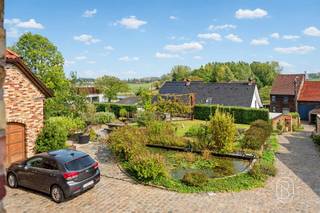 Karaktervol landhuis met eclectische charme, royale leefruimtes en prachtig groen uitzicht in Brakel!Bezoeknamiddag 31/10 van 14u30 tot 17u op inschrijving.Sommige woningen bezoek je. Andere beleef je.In het groene, landelijke decor van Brakel ontdek je deze bijzondere villa, waar rust, ruimte en karakter samenkomen. Een landhuis met een eigen ziel, waar landelijke charme, Franse kasteelinvloeden en verfijnde oosterse accenten elkaar ontmoeten in een verrassend eclectisch geheel. De combinatie van warme materialen, bijzondere details en uiteenlopende stijlinvloeden geeft deze woning een unieke uitstraling. Een plek waar authenticiteit en hedendaags wooncomfort hand in hand gaan.Indeling:Gelijkvloers: Een royale inkomhal biedt toegang tot een praktische bureauruimte, ideaal voor een vrij beroep, en een gastentoilet. De indrukwekkende, lichtrijke leefruimte met hoge plafonds en grote raampartijen creëert een prachtig samenspel tussen binnen en buiten. Aansluitend bevindt zich een tweede bureel met karaktervolle, gefreesde leistenen tegels die een elegante kasteelsfeer oproepen. Verder beschikt het gelijkvloers over een ruime keuken, bijkeuken, badkamer en een tweede volwaardige leefruimte. Twee sfeervolle salons met elk een eigen karakter, waar gezellig samenzijn en heerlijk tot rust komen elkaar afwisselen. Ook gelijkvloers wonen behoort tot de mogelijkheden.Eerste verdieping: 4 ruime slaapkamers, waaronder een lichtrijke mastersuite met dressing, en-suitebadkamer en privéwellness met infraroodcabine. Vanuit deze suite bereik je het royale privéterras met een prachtig uitzicht over de groene Brakelse velden.Zolder: Ruime zolderverdieping over het volledige dakoppervlak, ideaal als bijkomende opbergruimte.Tuin: De groene omgeving vormt een verlengstuk van de woning. Vanuit verschillende leefruimtes geniet je van een aangename verbinding met buiten, terwijl de tuin uitnodigt om in alle rust van het landelijke leven te genieten.Technisch: EPC-label B, conforme elektriciteit, gedeeltelijke nieuwbouw uit 2011, regenwaterput en aansluiting op de openbare riolering.Een woning waar verschillende stijlen en verhalen samenkomen, met de warmte van een echte thuis en de rust van het Brakelse platteland.Sommige plekken laten zich moeilijk in woorden vatten. Dit is er zo één. Laat je verrassen en plan jouw persoonlijke bezichtiging!Bezoek na afspraak met Immo Beguin, jouw vastgoedexpert sinds 2009.✉️ emmy@immobeguin.be