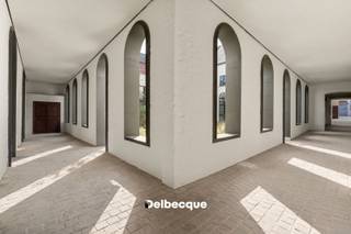 Het voormalige Karmelietessenklooster, één van de best bewaarde geheimen in het historische centrum van Brugge, krijgt dankzij een bijzondere herbestemming een nieuw leven. Het klooster wordt opgewaardeerd tot een klassevol woonproject waarin de oorspronkelijke erfgoedelementen zorgvuldig worden verweven met hedendaagse architectuur. Karmel omvat appartementen, woningen en één exclusieve kapelloft.<br /><br />De combinatie van dit historische kader met een privatieve tuin van maar liefst 5.000 m² maakt Karmel tot een uitzonderlijke plek om te wonen. Verscholen in het hart van Brugge geniet je hier van een bijzondere rust en privacy, op wandelafstand van alles wat de binnenstad te bieden heeft.<br /><br />De woning uit deze advertentie is zonder twijfel één van de blikvangers van het project: de unieke kapelloft. De oorspronkelijke neogotische kapel dateert uit 1877 en wordt gekenmerkt door haar zes traveeën, spitsboogvensters, spitsboognis en het indrukwekkende spitsbooggewelf met trekankers. Bij de herbestemming tot loft blijft het karakter en de ruimtelijkheid van de voormalige kapel maximaal behouden.<br /><br />De royale leefruimte vormt het hart van de loft en straalt dankzij de hoge gewelven en authentieke architectuur een uitzonderlijk gevoel van ruimte en klasse uit. Het grote raam ter hoogte van de keuken biedt een prachtig en open zicht op de uitgestrekte kloostertuin. Een draaitrap verbindt de leefruimte met een hoger gelegen bureauruimte, die uitkijkt over de loft.<br /><br />Op het gelijkvloers bevindt zich eveneens de master bedroom met aansluitende badkamer. Op de bovenverdieping zijn twee bijkomende slaapkamers en een tweede badkamer voorzien.<br /><br />De grootste werken zijn intussen achter de rug. Als koper krijg je nog de ruimte om de laatste afwerkingskeuzes zelf te maken en de kapelloft zo verder vorm te geven volgens je eigen stijl. De hoogwaardige basisafwerking omvat onder meer eiken parket, uitgeruste badkamers en een keuken met natuurstenen werkblad en toestellen. De laatste materiaal- en interieurkeuzes kan je als koper nog mee bepalen.<br /><br />Ook op het vlak van duurzaamheid en technisch wooncomfort werd Karmel toekomstgericht uitgewerkt. De kapelloft is bijzonder compleet uitgerust met geothermische verwarming en koeling, vloerverwarming, ventilatiesysteem D met warmterecuperatie, zonnepanelen en regenwaterrecuperatie.<br /><br />Karmel combineert zo een unieke historische locatie met rust, ruimte, klasse en modern wooncomfort, midden in het centrum van Brugge.<br /><br />Wil je deze bijzondere kapelloft en de site zelf ontdekken? Contacteer ons voor een bezoek ter plaatse via 050 45 03 45 of info@delbecque.immo.