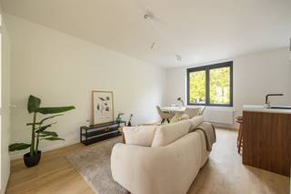 <p><span> </span></p><p><span>Strak gerenoveerd, energiezuinig én helemaal instapklaar: dit appartement van ca. 67 m² op de eerste verdieping heeft het allemaal. Je krijgt een heerlijk lichte leefruimte met open keuken, twee slaapkamers en een stijlvolle badkamer, afgewerkt in warme houttinten. En dat in een fijne buurt van Berchem, met het Brilschanspark en natuurgebied Wolvenberg op wandelafstand.</span><span> </span></p><p><span> </span></p><p><span>Lichte leefruimte met warme leefkeuken</span></p><p><span>Je komt het appartement binnen in de centrale hal, van waaruit je meteen doorloopt naar de leefruimte vooraan. Hier is lekker veel plaats voor een ruime zithoek en een grote eettafel. Het kamerbrede raam trekt veel natuurlijk licht binnen en de warme parketlaminaat loopt mooi door in het hele appartement. De zwarte pvc-ramen met driedubbele beglazing zorgen voor een strak accent én extra comfort. De open keuken past perfect in dat plaatje. De donkerbruine houtlook kasten geven de ruimte warmte, terwijl het lichte werkblad en het donkere kraanwerk het geheel strak houden. Het grote kookeiland met spoelbak doet tegelijk dienst als gezellige ontbijtogen: ideaal om er een paar barkrukken bij te schuiven. Ook praktisch is alles voorzien, met Samsung-toestellen zoals een combioven en vaatwasser en een Elica inductievuur met ingebouwde afzuiging. </span></p><p><span> </span></p><p><span>Twee slaapkamers & stijlvolle badkamer</span></p><p><span>Via de lange hal ga je naar de twee slaapkamers. De eerste is leent zich perfect als kinder-, logeer- of werkkamer. De master bedroom biedt ruim plaats aan een dubbel bed en extra kasten. Ook hier zorgen de grote ramen met driedubbele beglazing voor natuurlijk licht. De badkamer sluit helemaal aan bij de rustige, hedendaagse stijl van het appartement. Je hebt er een ruime inloopdouche met grijze betegeling en regendouche, een zwevend houtlook meubel met witte opbouwwastafel en donker geborsteld kraanwerk. Het toilet is netjes geïntegreerd in dezelfde ruimte. In de hal vind je bovendien nog een aparte berging van met aansluiting voor je wasmachine. Hier zitten ook de elektrische Ariston-boiler en de Vaillant-omvormer van de privatieve zonnepanelen netjes uit het zicht. </span></p><p><span> </span></p><p><span>Groen wonen in Berchem</span></p><p><span>Hier combineer je stad en groen zonder moeite. Het Brilschanspark en het mooie natuurgebied Wolvenberg liggen op wandelafstand, en ook sportcentrum Het Rooi is vlakbij. Voor je dagelijkse boodschappen vind je supermarkten enkele straten verder. Zin in een koffie, restaurant of wat winkels? Dan sta je zo in Oud-Berchem, de Pulhofwijk of Groenenhoek. </span></p><p><span>Ook energetisch zit je hier bijzonder goed. Het appartement haalt EPC A en is voorzien van privatieve zonnepanelen, elektrische verwarming, driedubbele beglazing en ventilatiesysteem C+. Voeg daar conforme elektriciteit en een asbestveilig attest aan toe en je hebt een appartement waar je zonder grote werken meteen je dozen kunt uitpakken. </span></p><p><span> </span></p><p><span> </span></p>